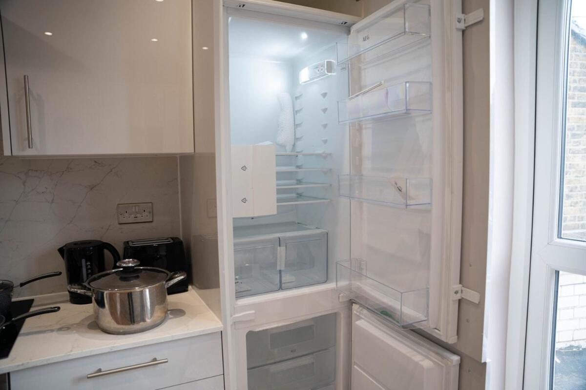a kitchen with white cabinets and a glass refrigerator at Spacious 2BR, Fast Trains - Calm South London Stay in London +34 photos