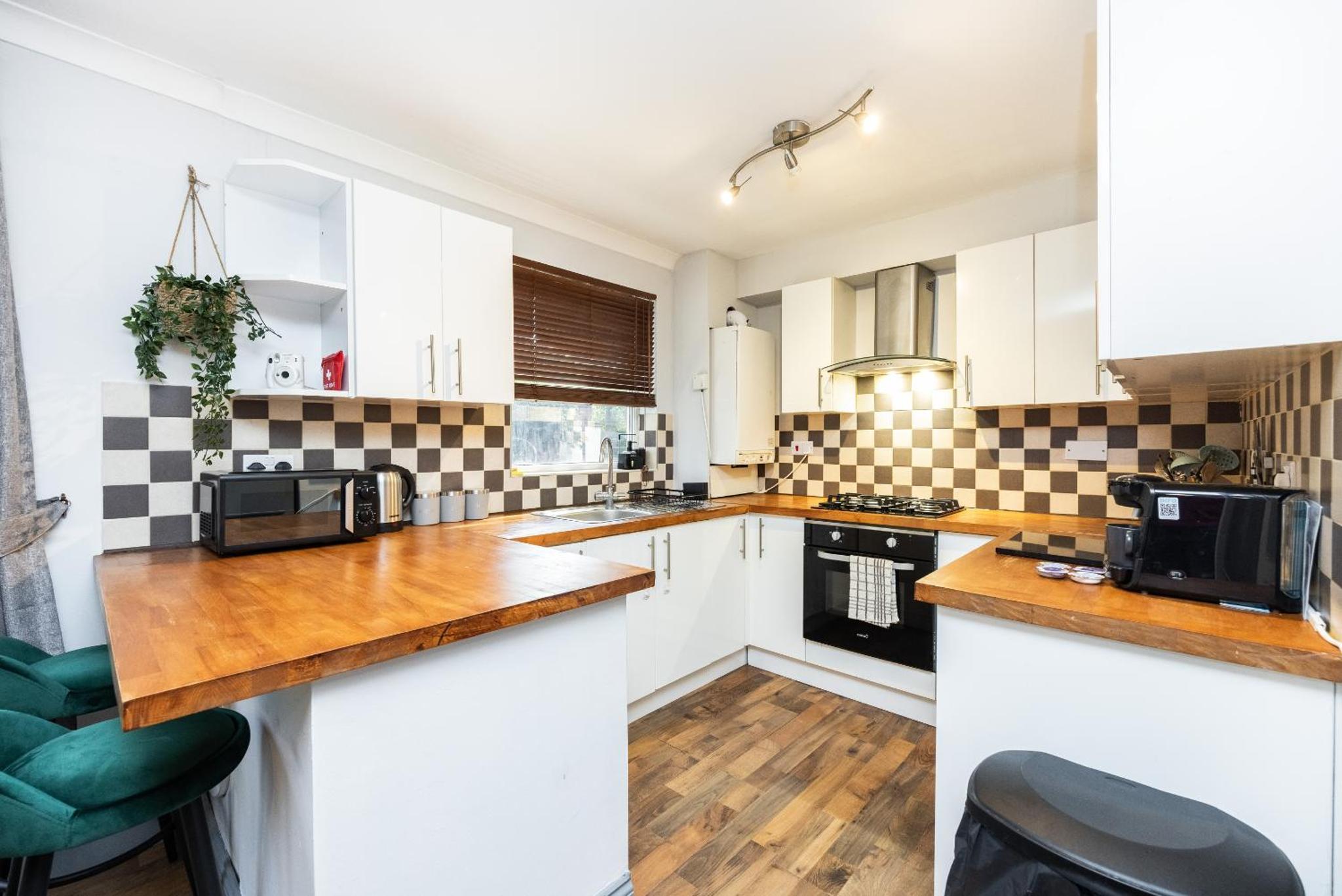 a kitchen with white cabinets and wooden counter tops at Kings Cross Camden Suite in London