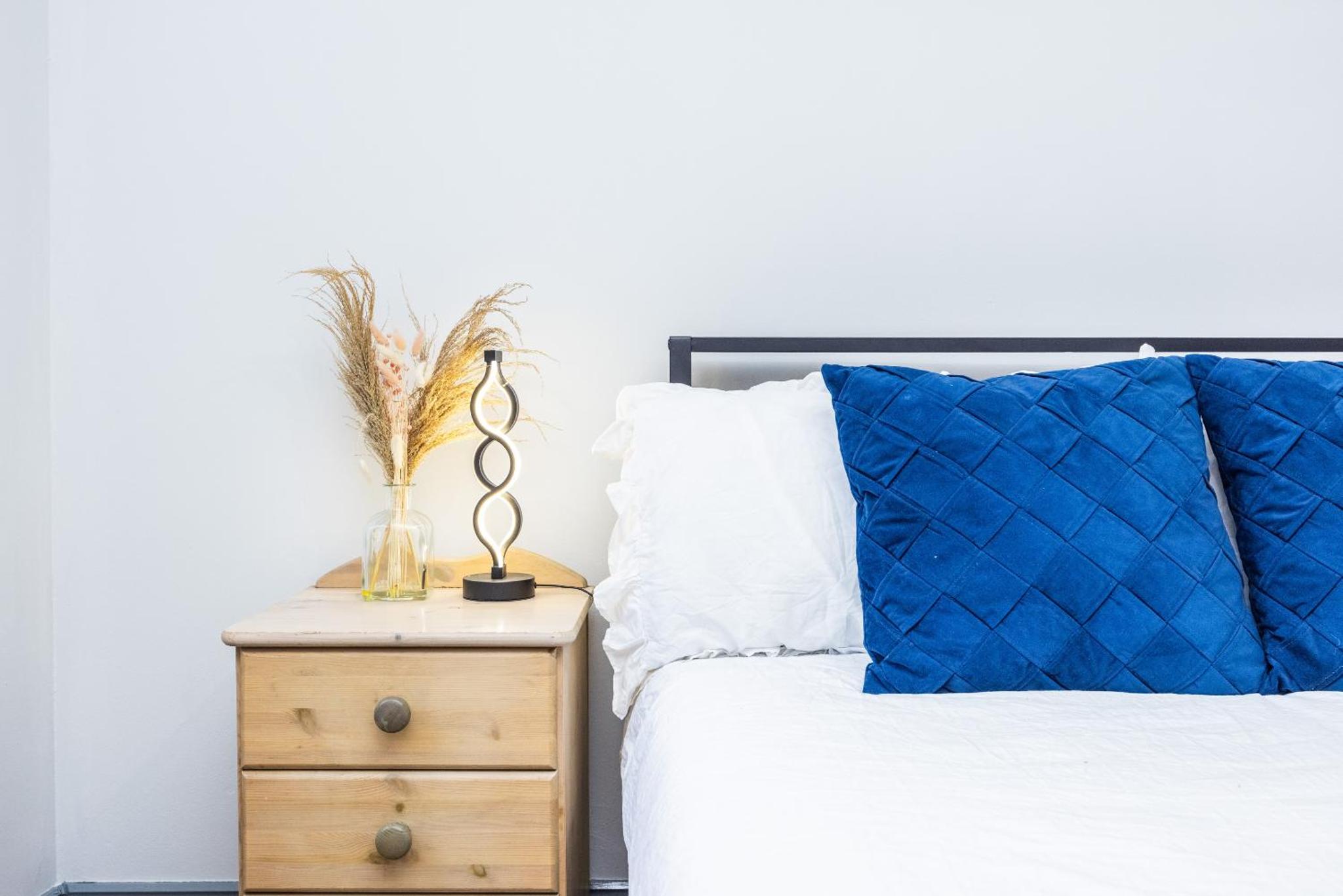 a bedroom with a bed and a nightstand with a blue pillow at Kings Cross Camden Suite in London