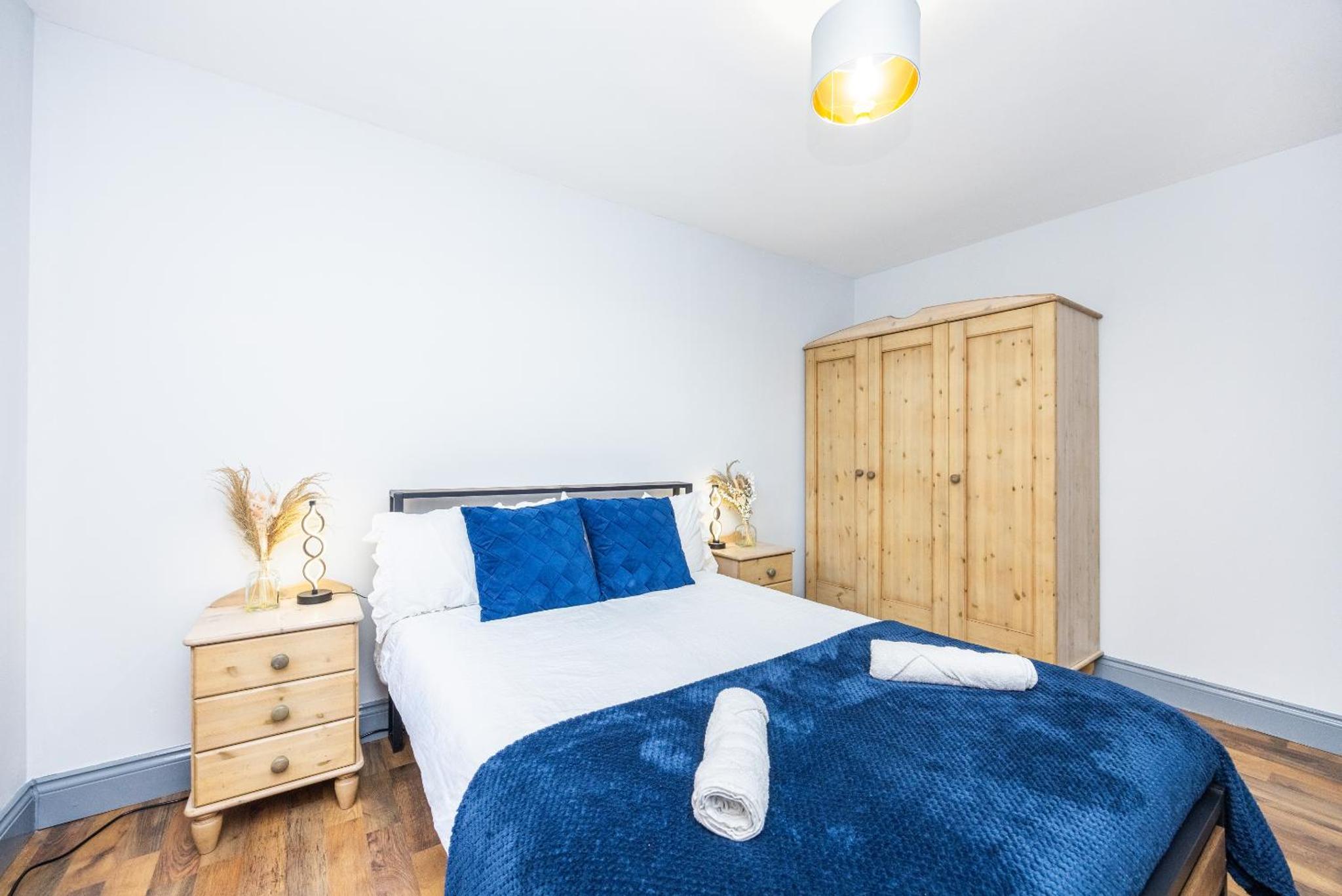 a bedroom with a large bed and a wooden cabinet at Kings Cross Camden Suite in London