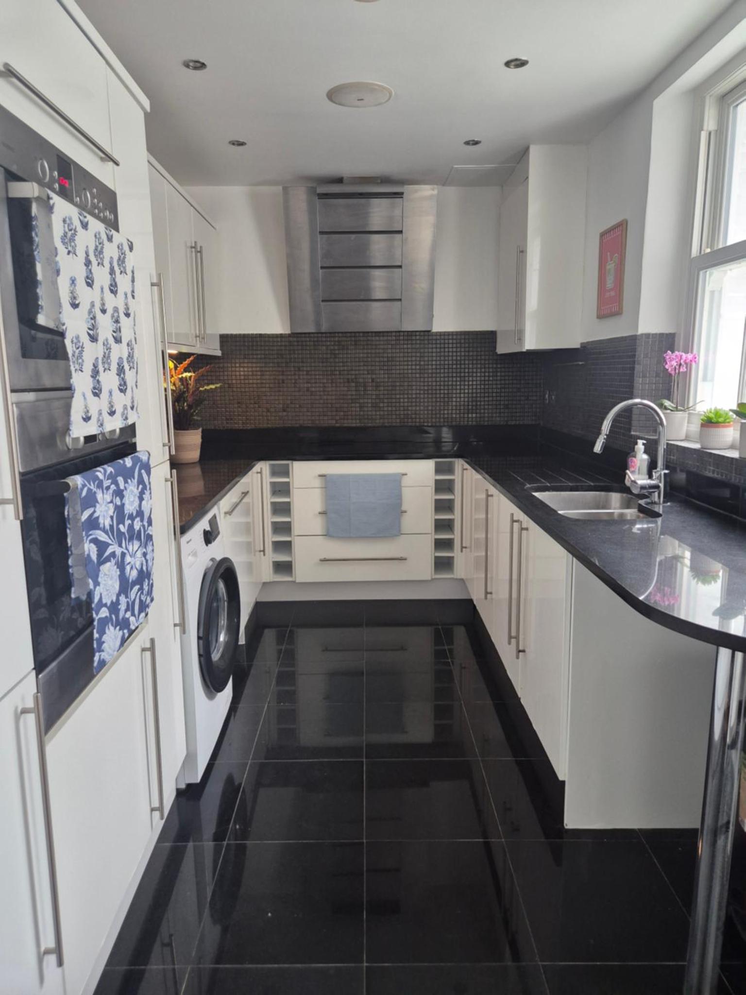 a kitchen with white appliances and a black floor at Bright 4 double bedroom victorian house in London +11 photos