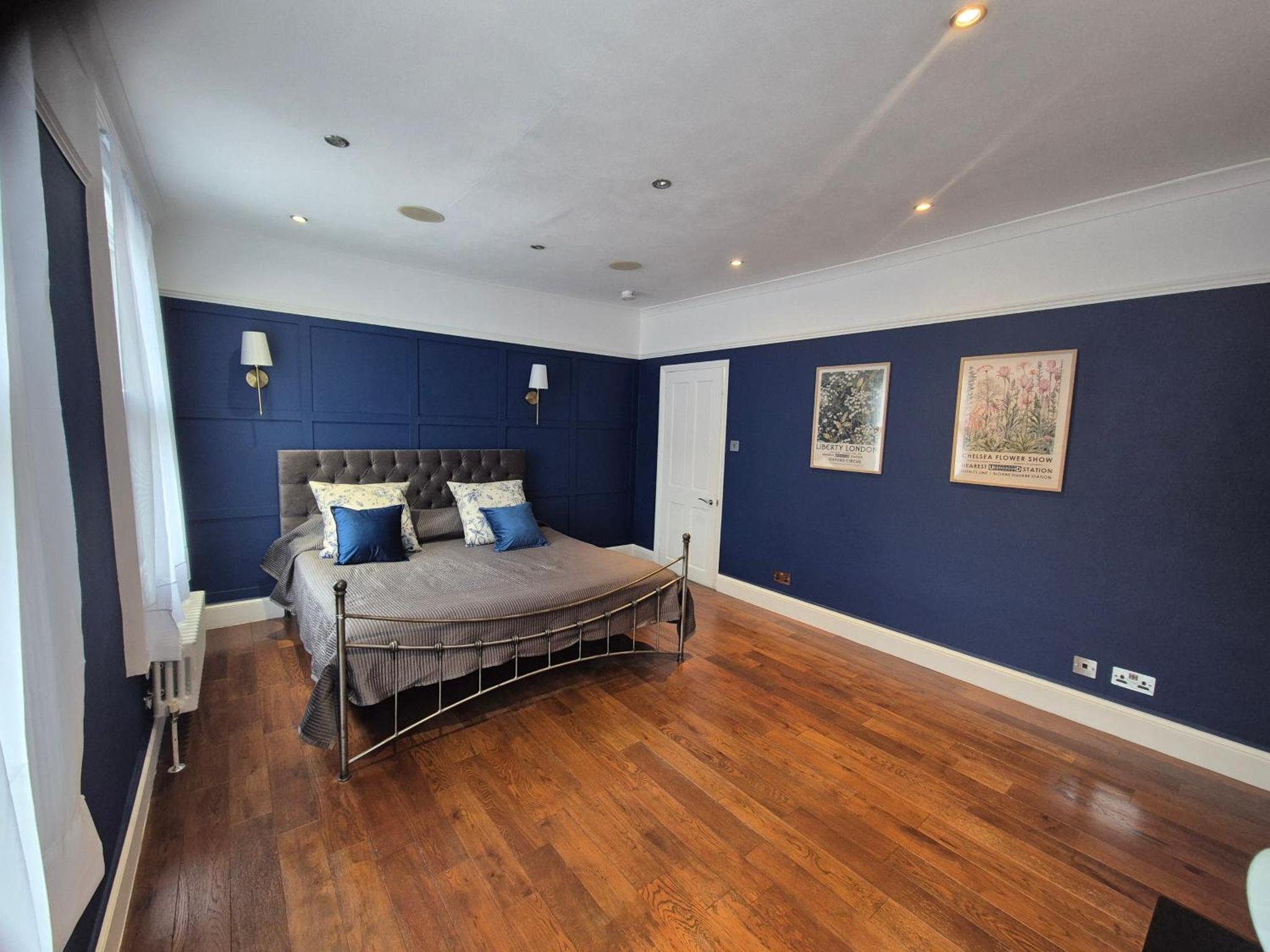 a bedroom with blue walls and a bed with blue pillows at Bright 4 double bedroom victorian house in London