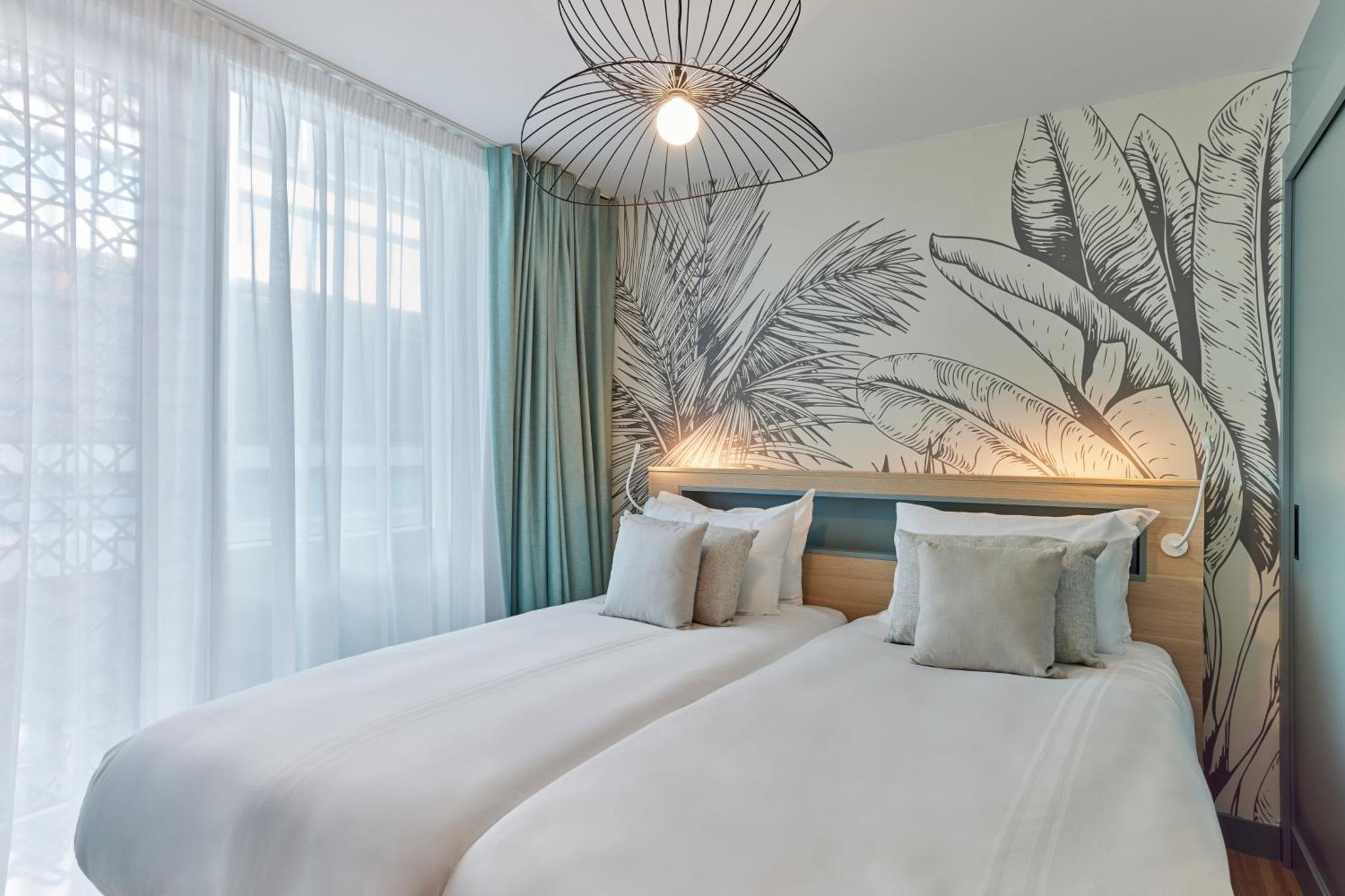 a bedroom with two beds with white sheets and a plant mural at Aparthotel Adagio London City East in London