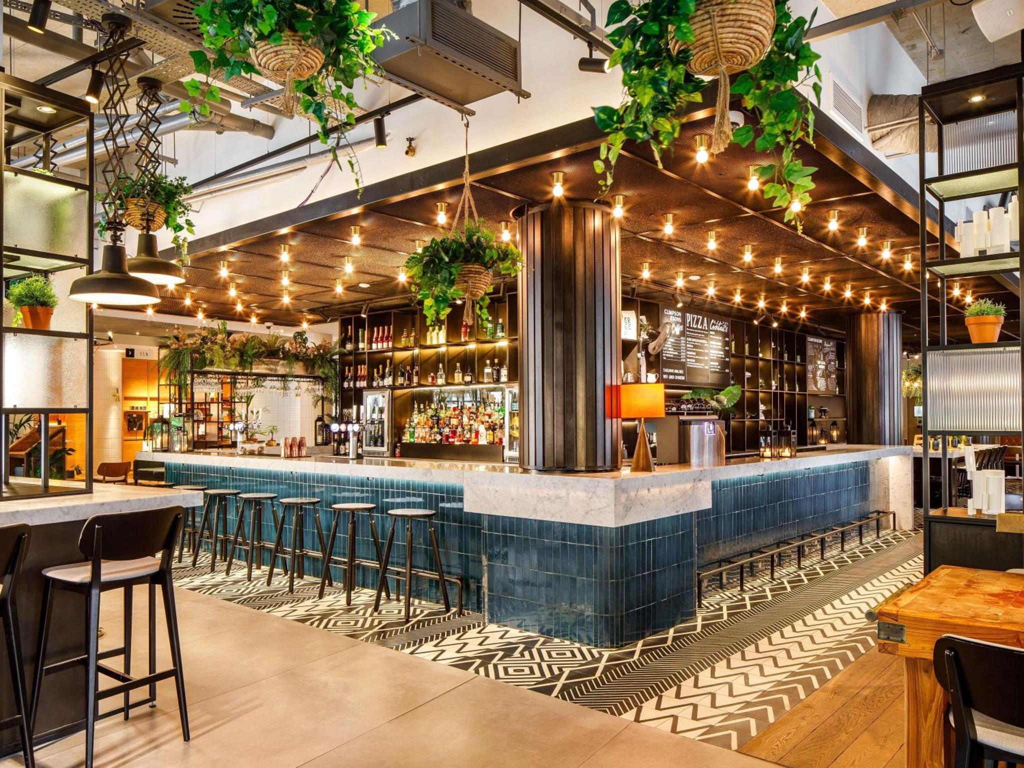 a bar with plants hanging from the ceiling at Novotel London Bridge in London