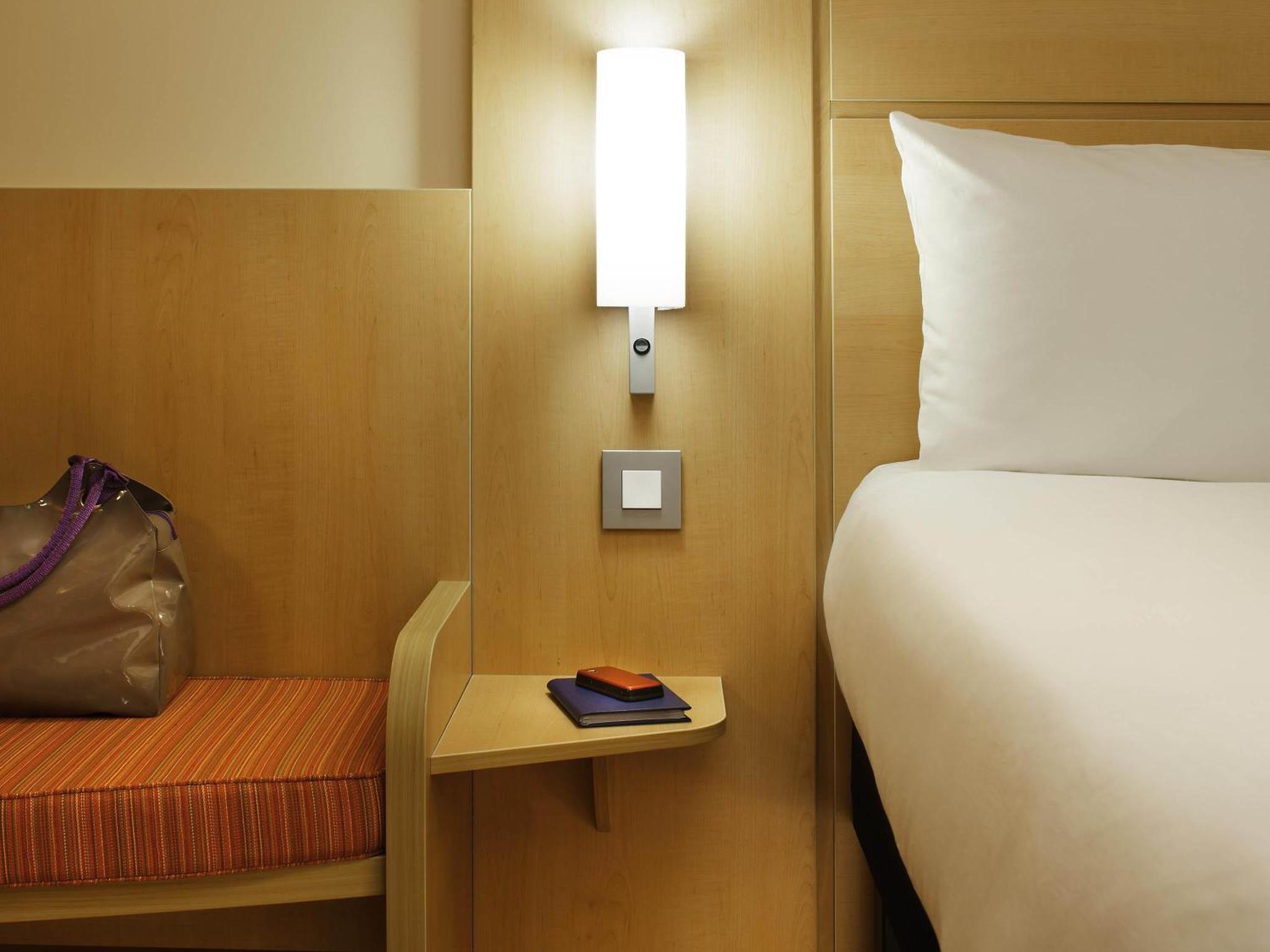 a hotel room with a bed and a table with a book at ibis London Shepherds Bush - Hammersmith in London +66 photos