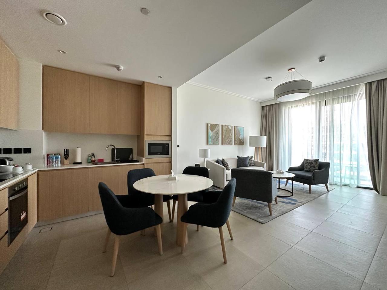 a kitchen and a living room with a table and chairs at Address Vista Bahrain in Rayyā