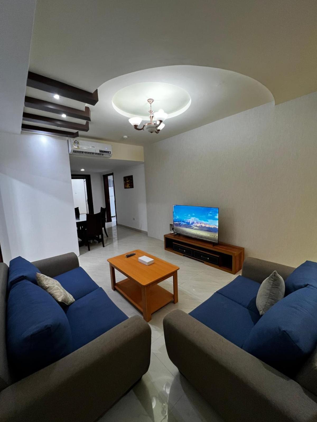 a living room with two blue couches and a flat screen tv at Oryx Tower in Manama