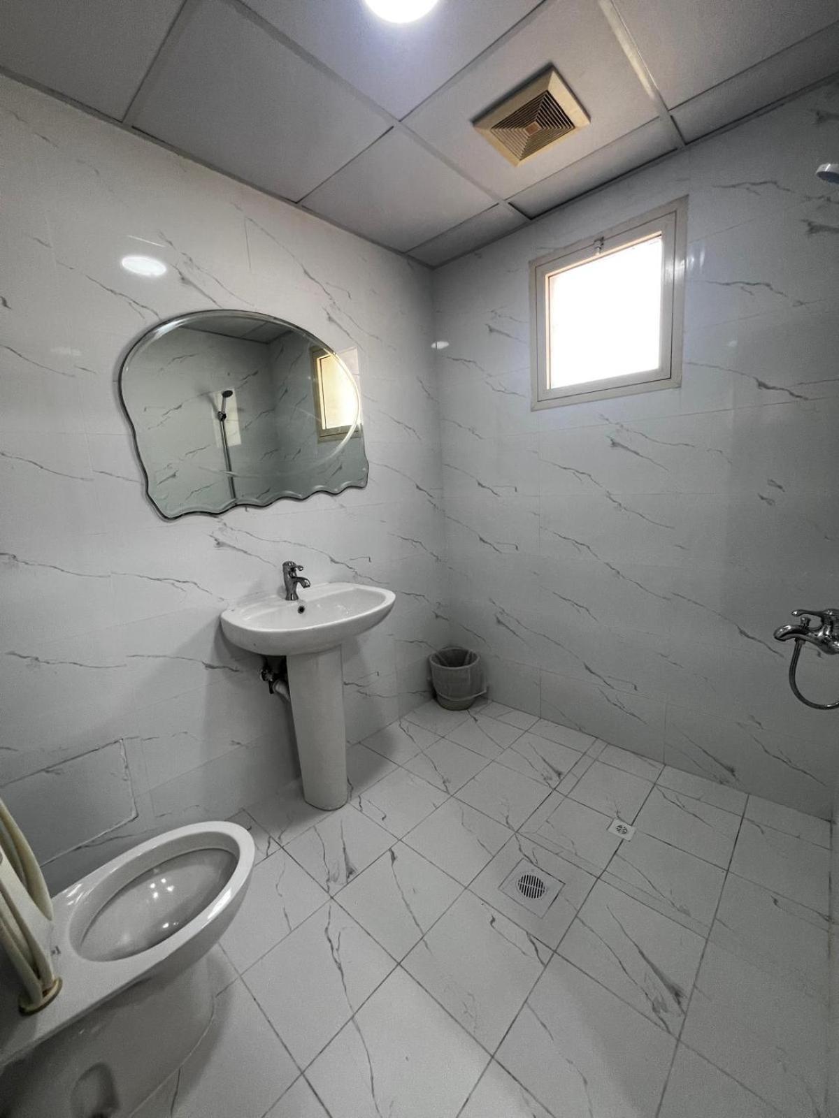 a white bathroom with a sink and a toilet at Oryx Tower in Manama