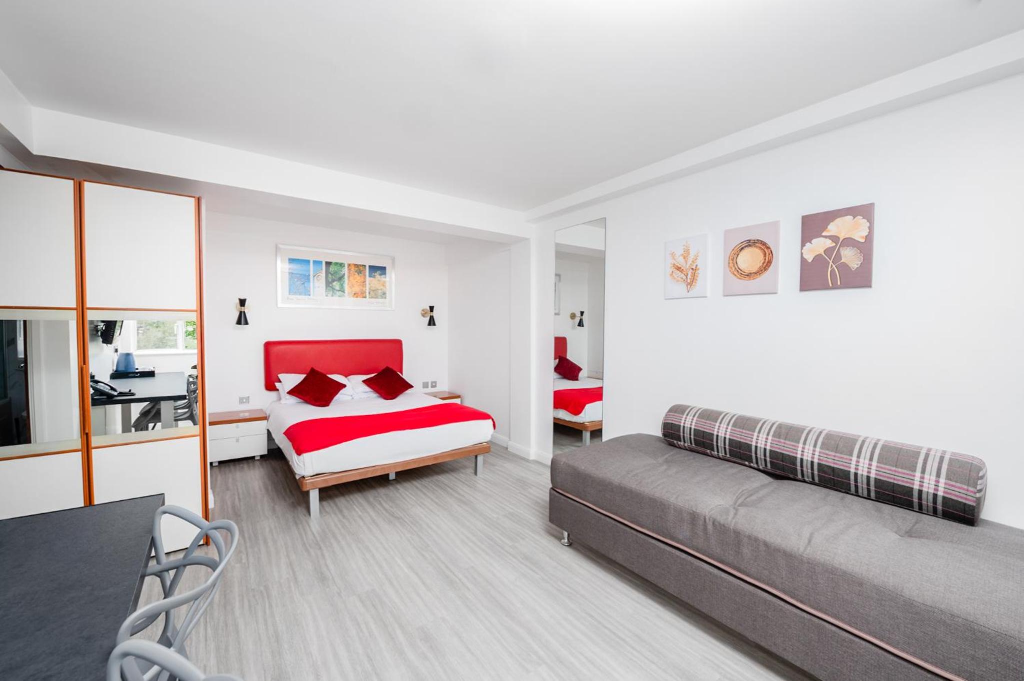 a bedroom with two beds and a desk at Roland House in London