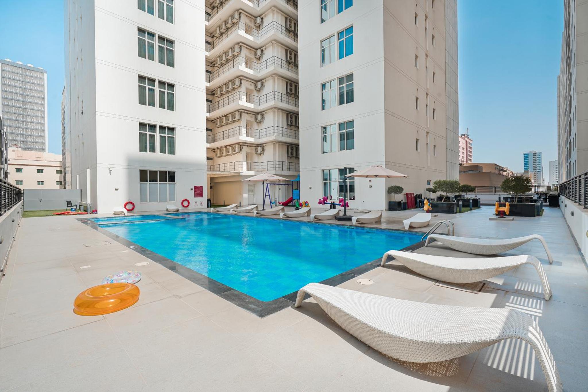 a swimming pool in a building with lounge chairs at Eden Garden Hotel Apartment in Manama