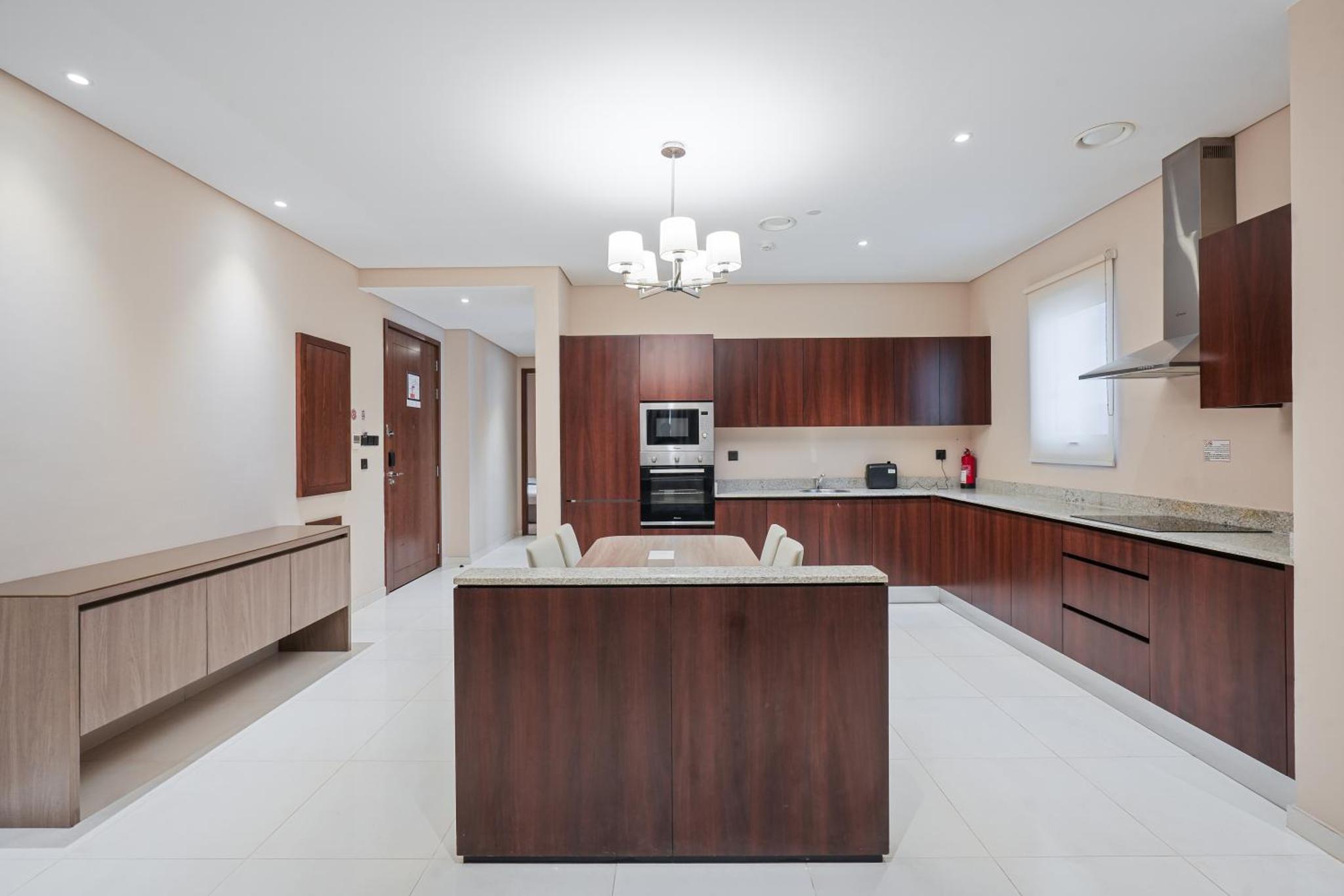 a large kitchen with wooden cabinets and a large island at Eden Garden Hotel Apartment in Manama