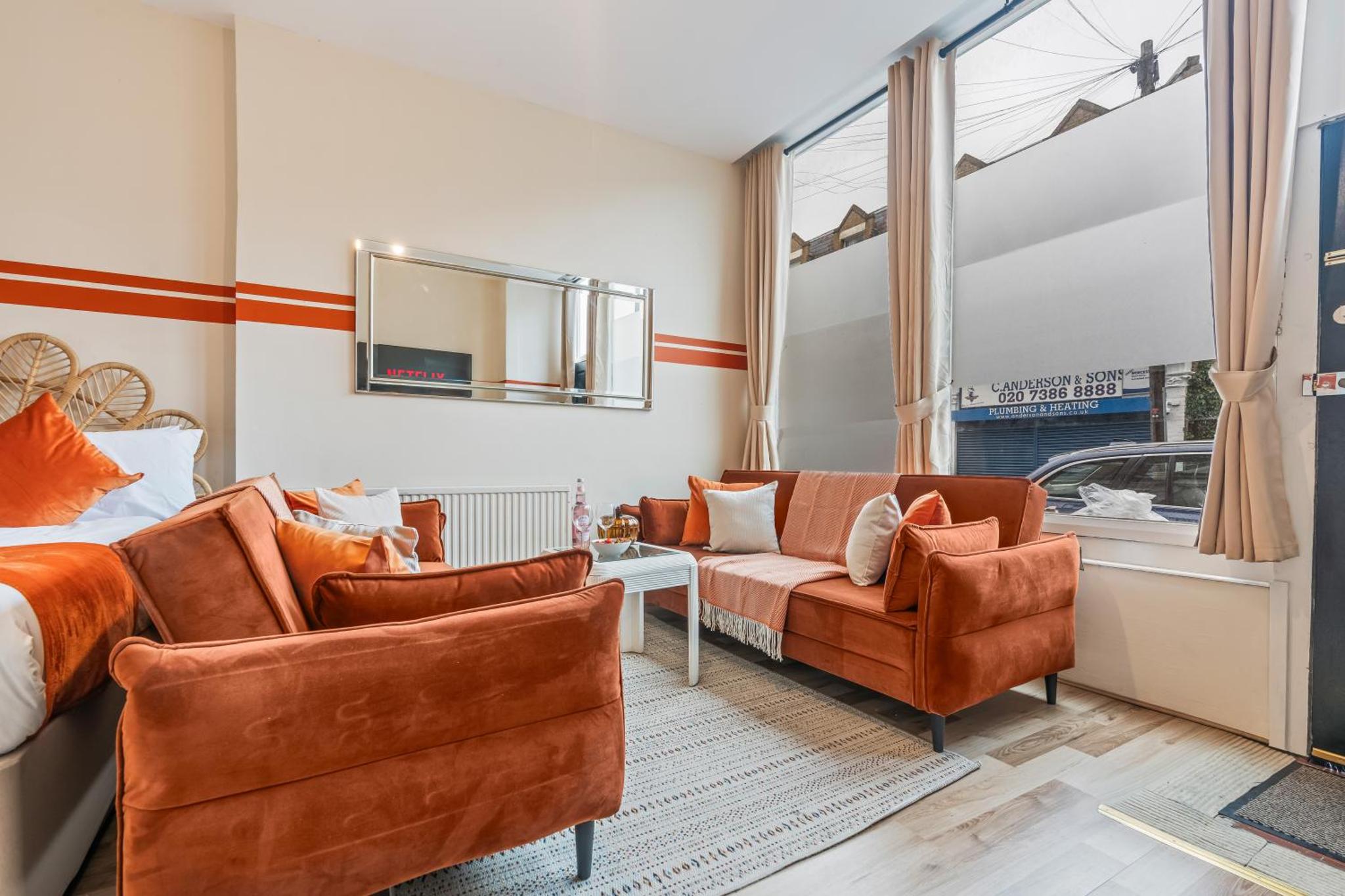 a hotel room with a bed and two chairs and a mirror at Stylish 3 Bed Fulham Sleeps 10, Stamford Bridge in London