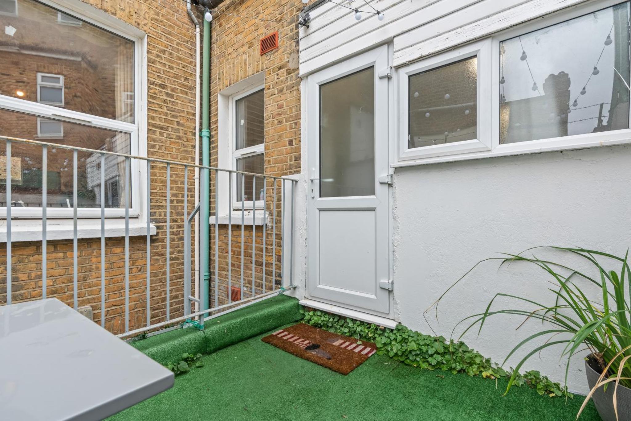 a front door of a house with green grass at Stylish 3 Bed Fulham Sleeps 10, Stamford Bridge in London