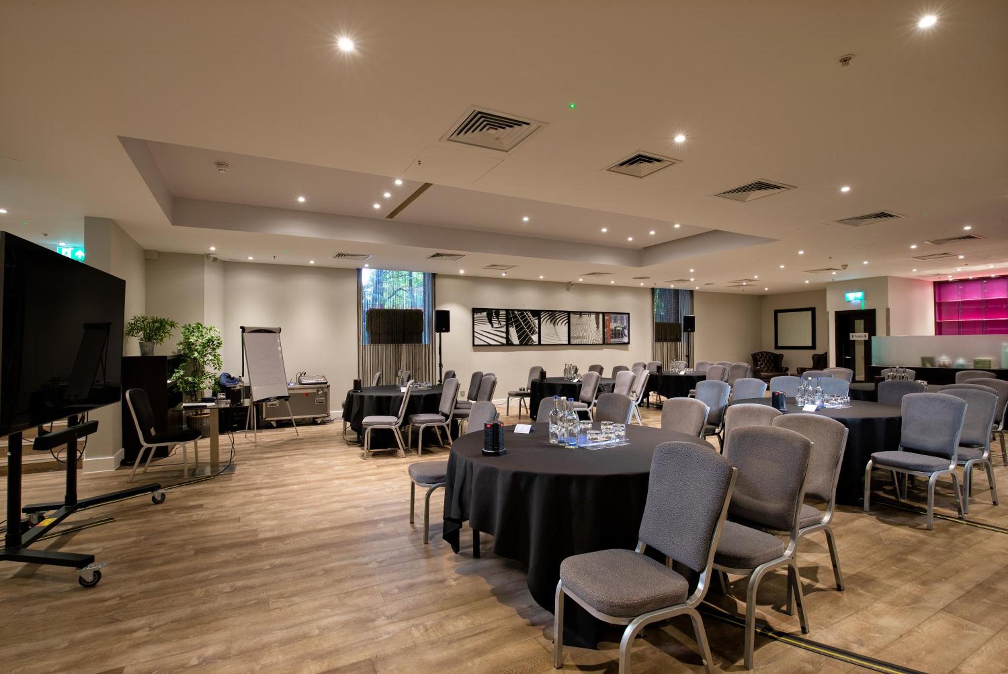 a conference room with tables and chairs and a screen at Hilton London Kensington Hotel in London