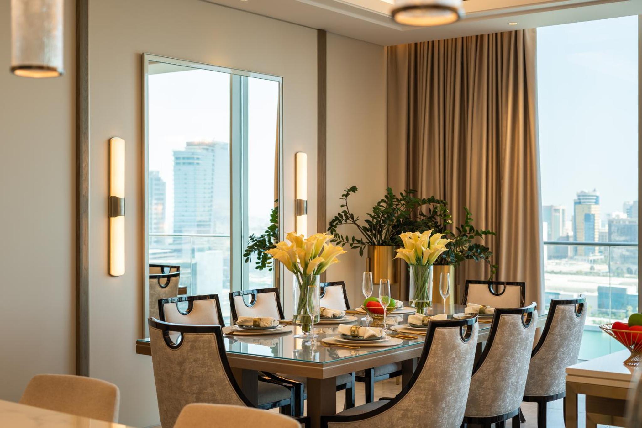 a dining room with a table and chairs and a large window at Onyx Rotana in Manama