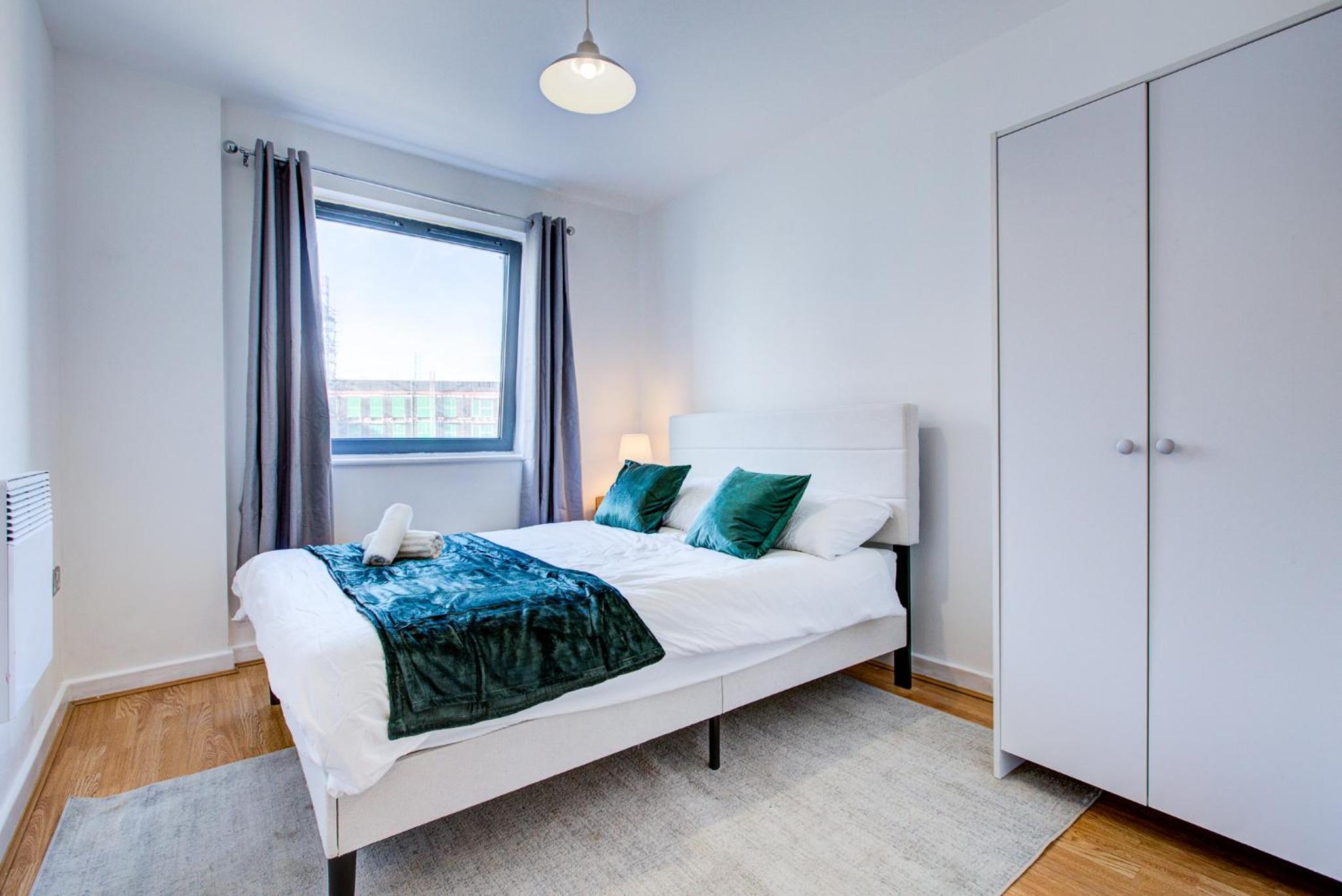 a bedroom with a white bed and a window at Luxury apartment in Stratford in London
