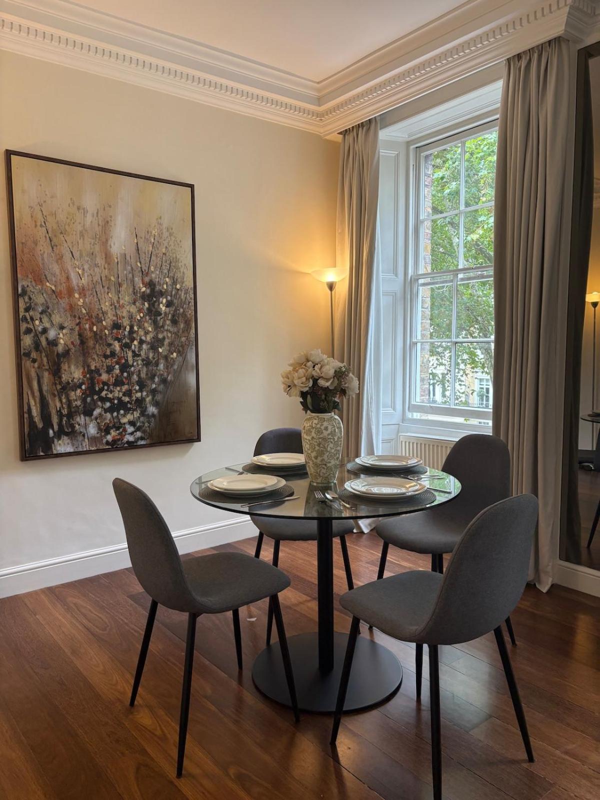 a dining room with a table and chairs and a painting at Stylish 1 Bed in Knightsbridge Prime Location in London