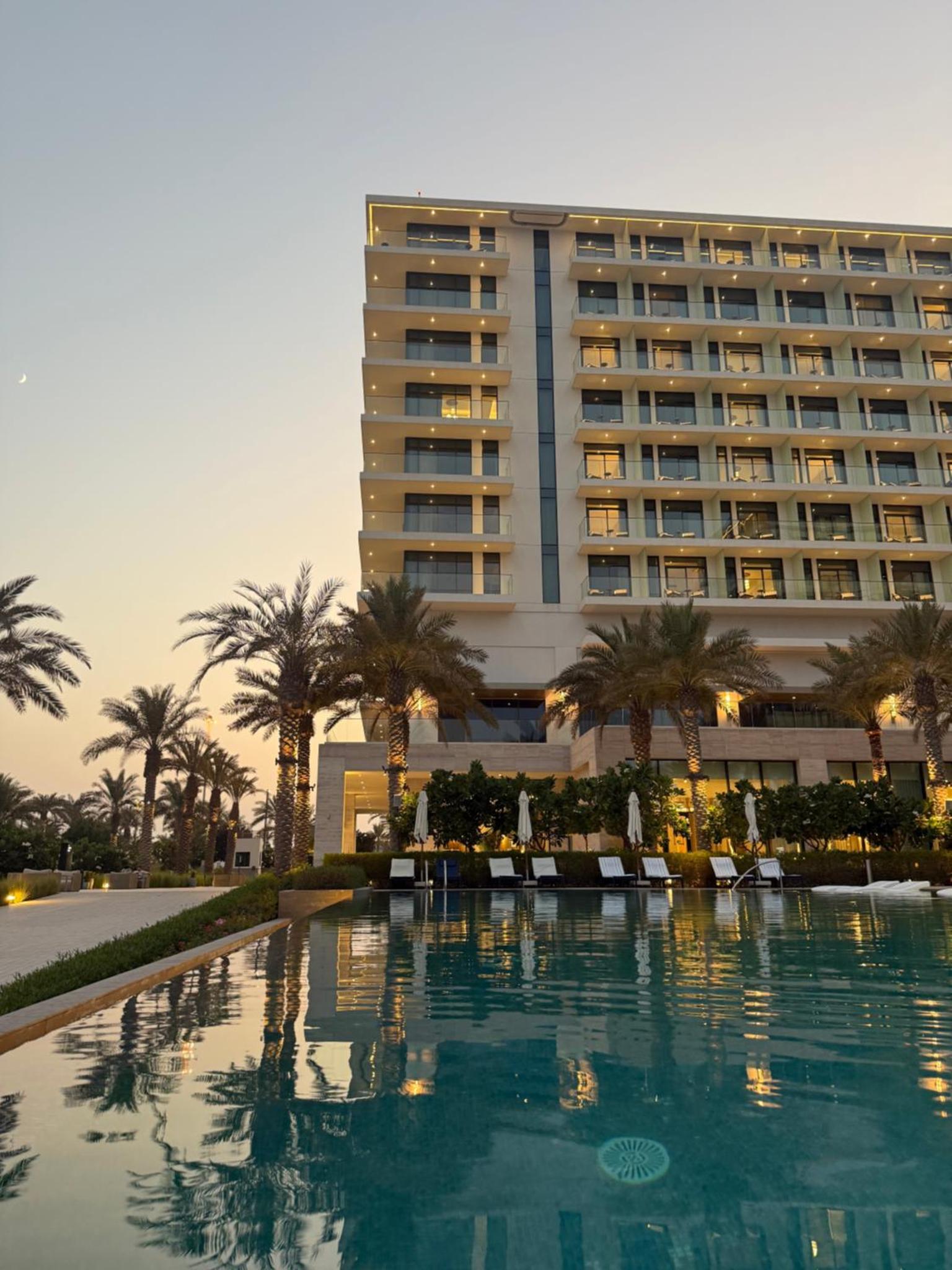 a hotel with a pool in front of a building at Address Residences Beach Resort Bahrain in Rayyā