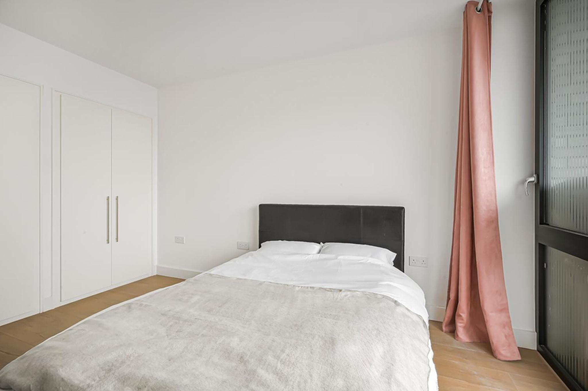 a bedroom with a large bed with a black headboard at CANARY WHARF E14 MODERN 1 Bed APARTMENT HIGH SPEC in London