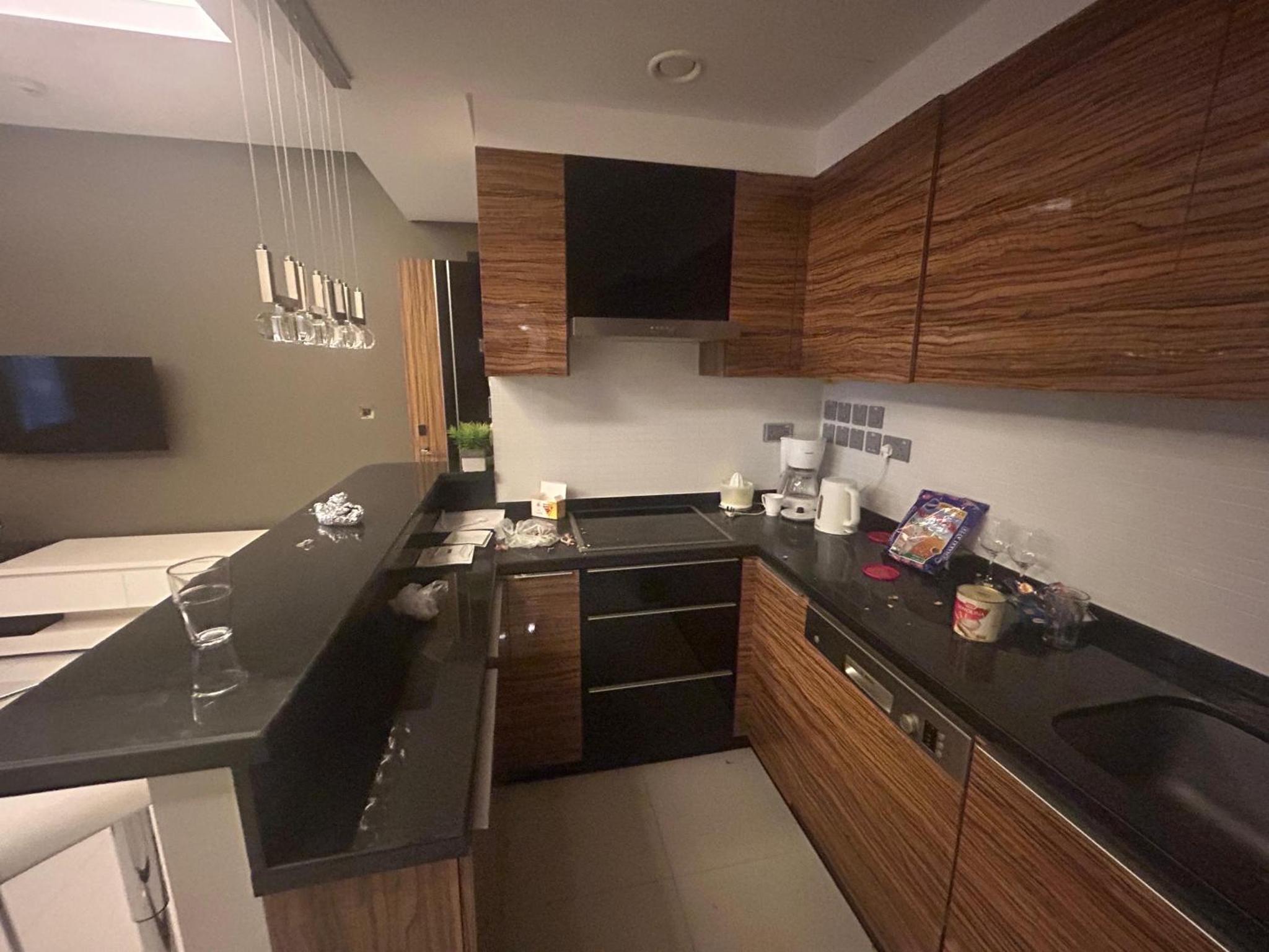 a kitchen with black counter tops and wooden cabinets at Your dream place 1 BHK near City Centre Bahrain in Manama