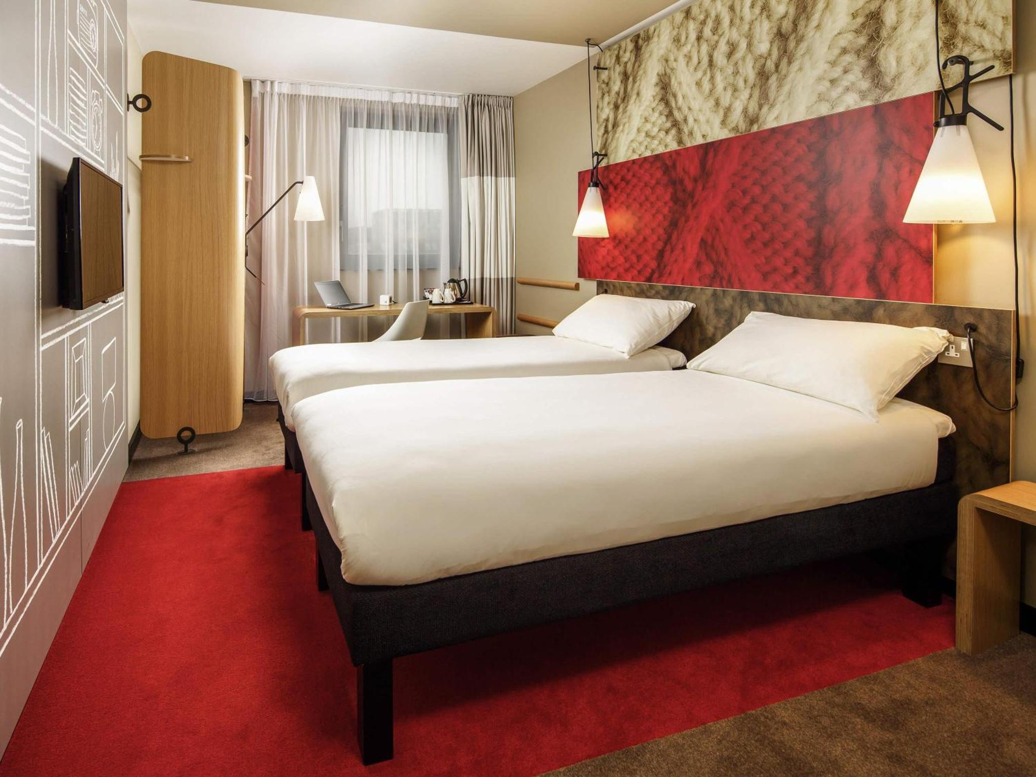 a hotel room with two beds and a red carpet at ibis London Docklands Canary Wharf in London