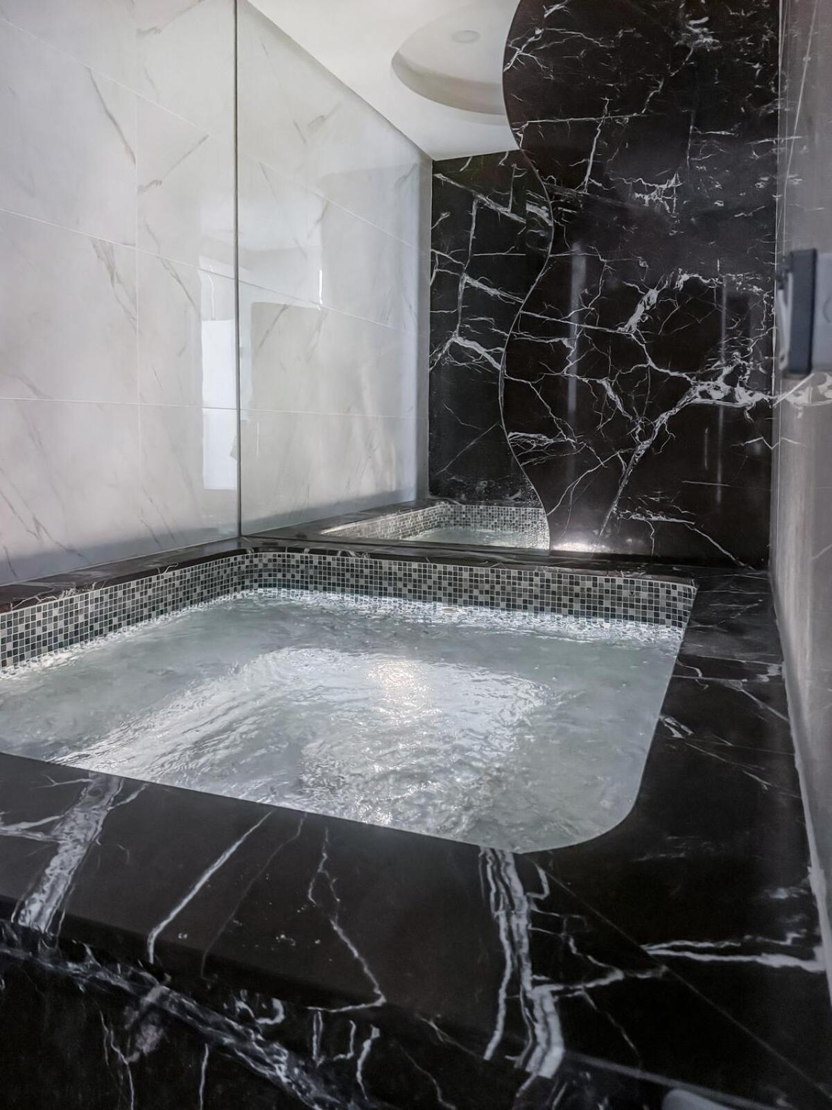 a bathroom with a jacuzzi tub with black marble at 2BR Four Season View in Water Bay in Manama