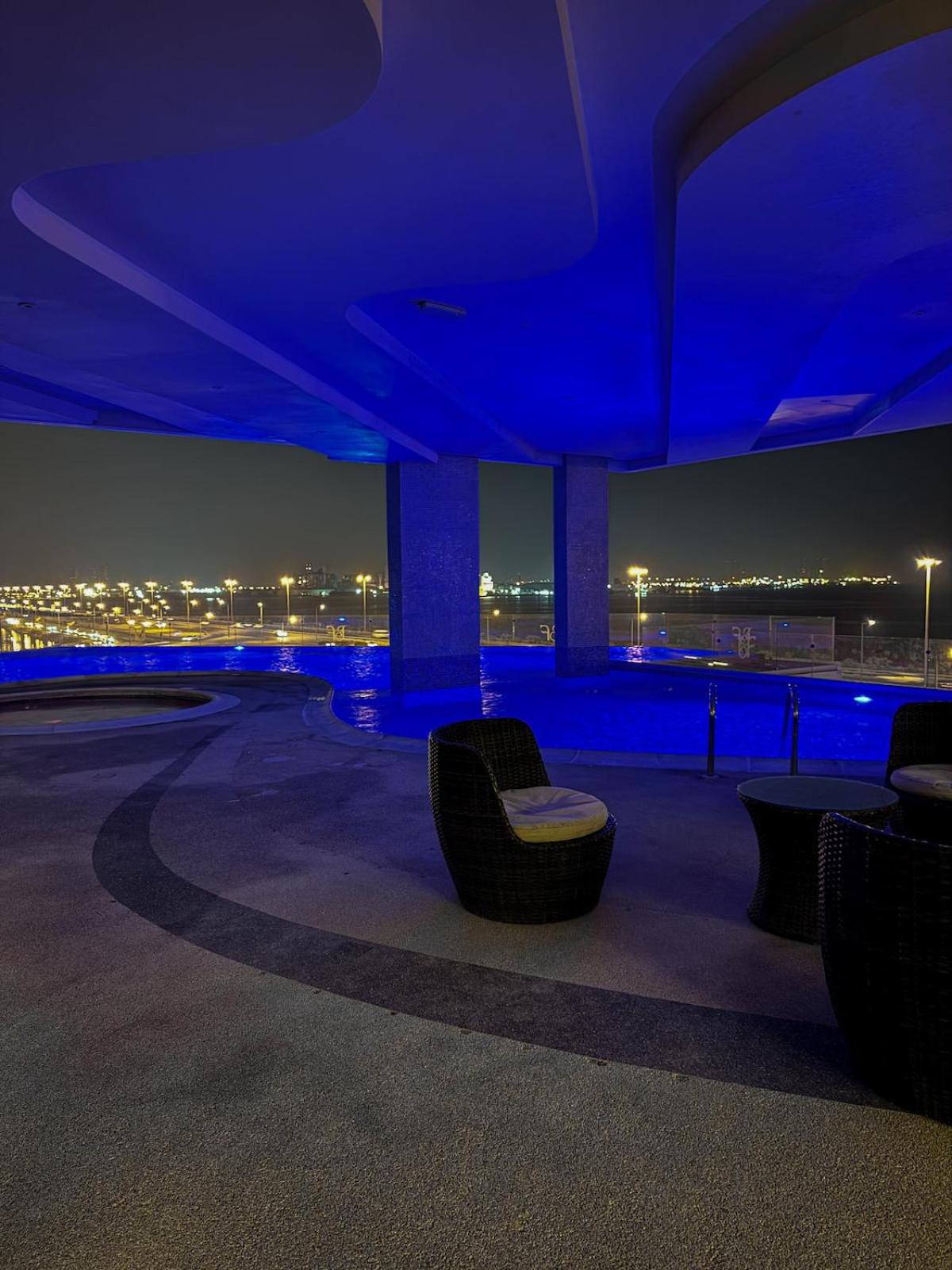a night view of a building with chairs and lights at Skyline Suite in Hidd Heights in Manama