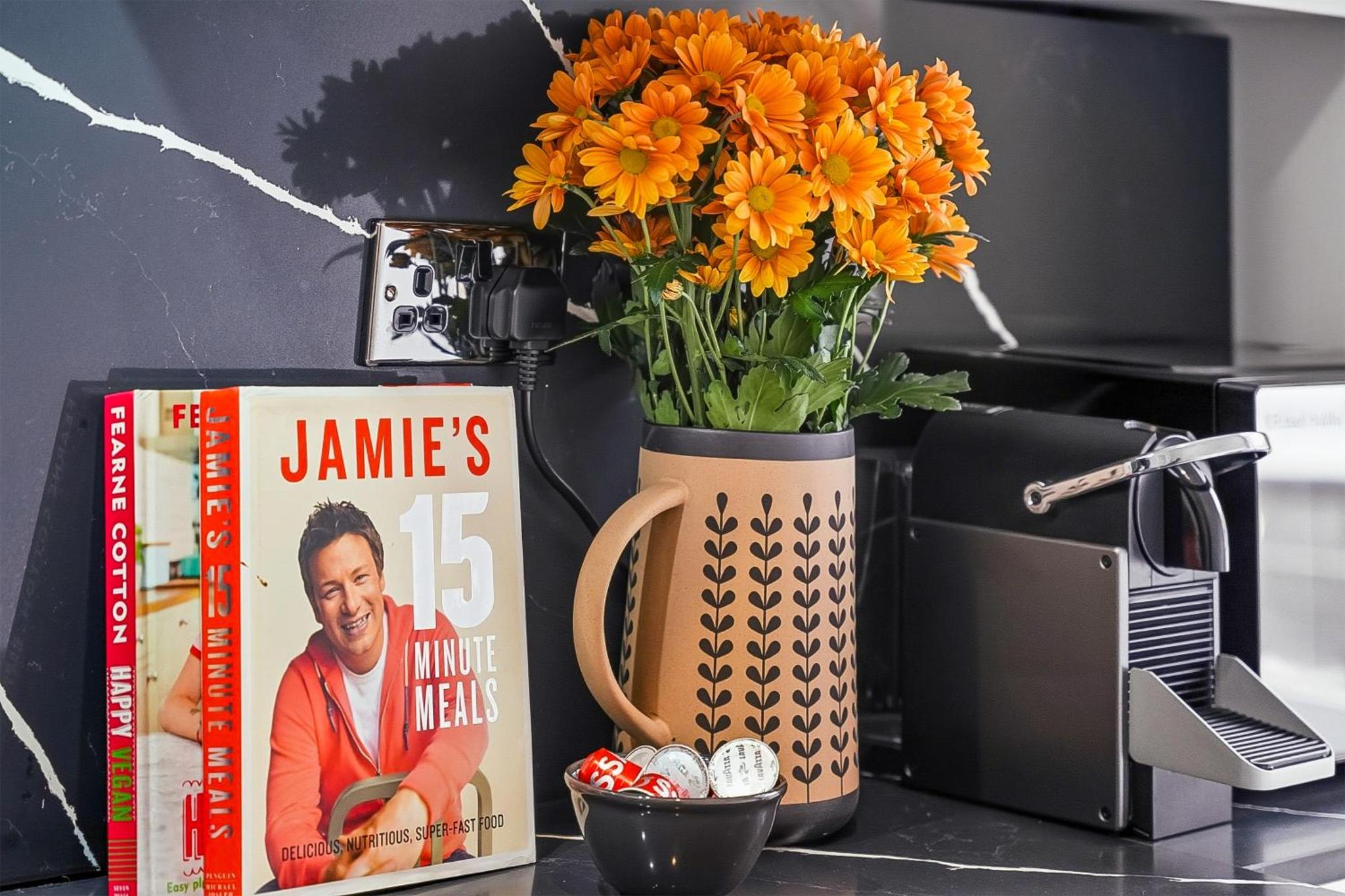 a vase filled with orange flowers next to a book at Bright & Stylish Flat in the Heart of Islington in London