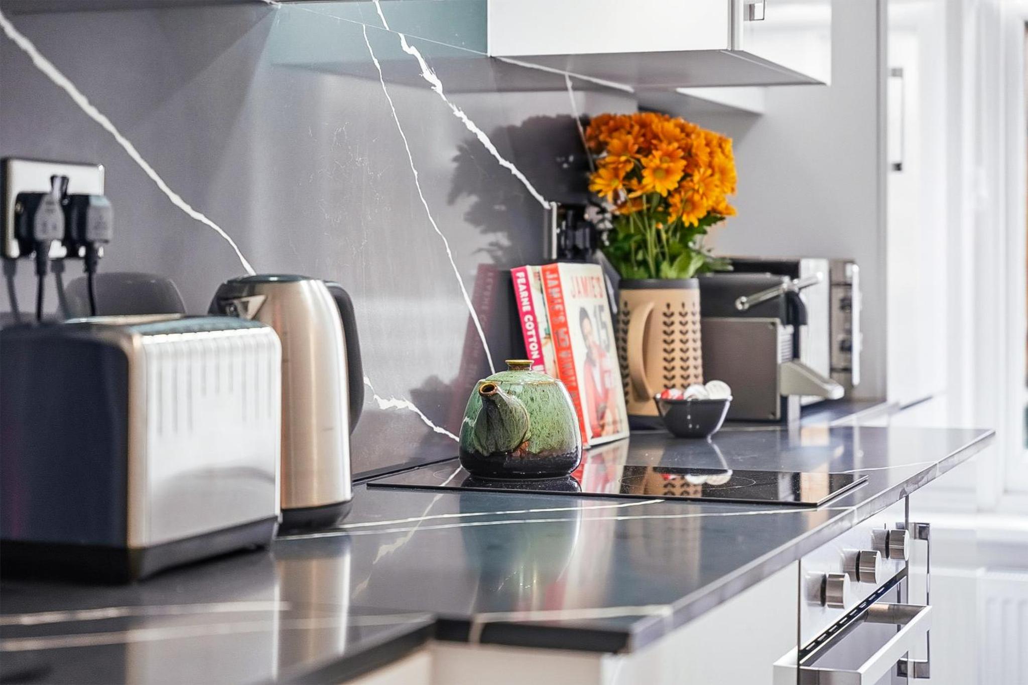 a kitchen with a counter top with flowers on it at Bright & Stylish Flat in the Heart of Islington in London +21 photos
