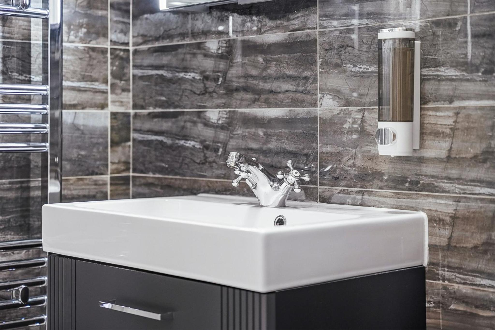 a white sink in a bathroom with a wall at Bright & Stylish Flat in the Heart of Islington in London