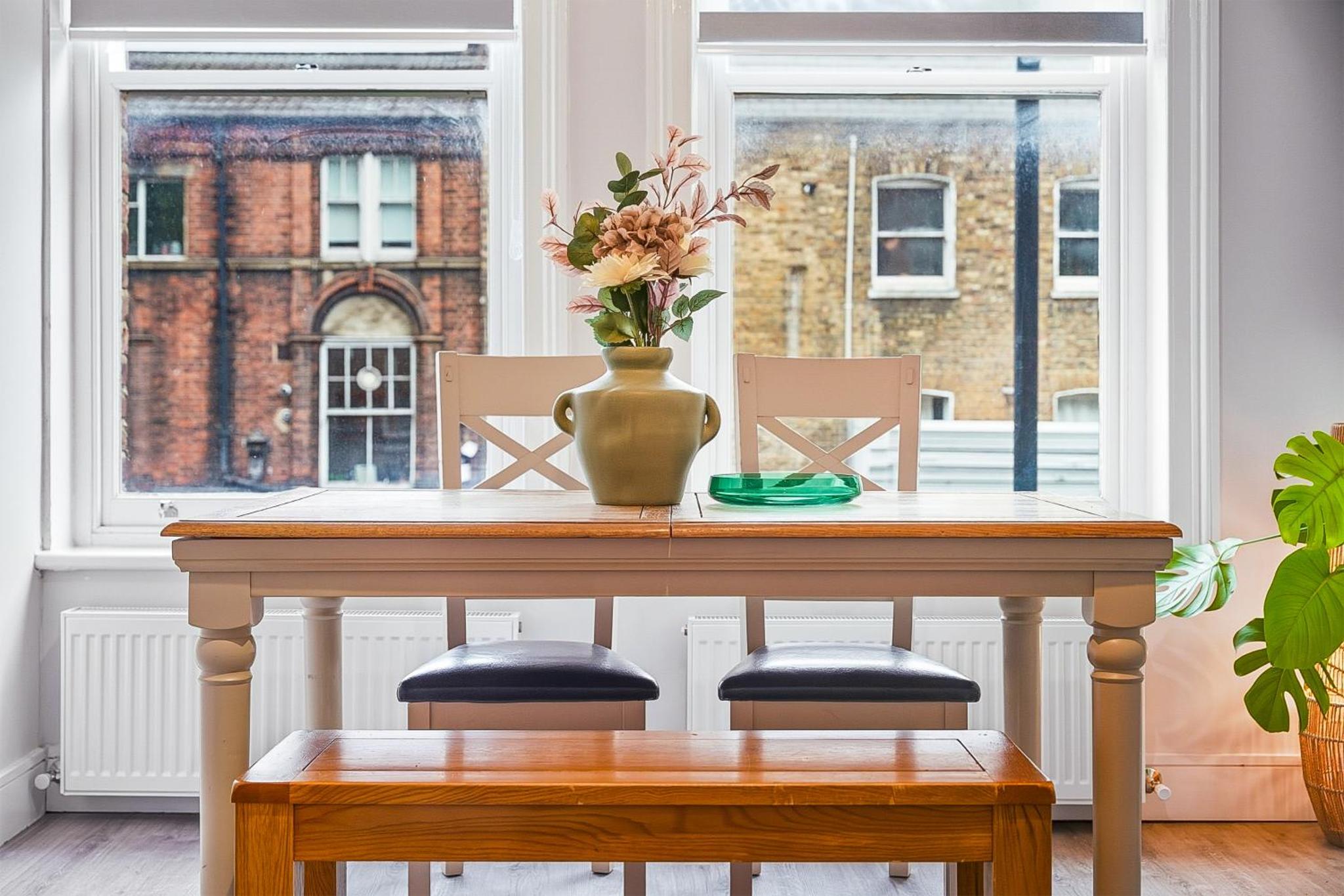 a table with two chairs and a vase with flowers on it at Bright & Stylish Flat in the Heart of Islington in London