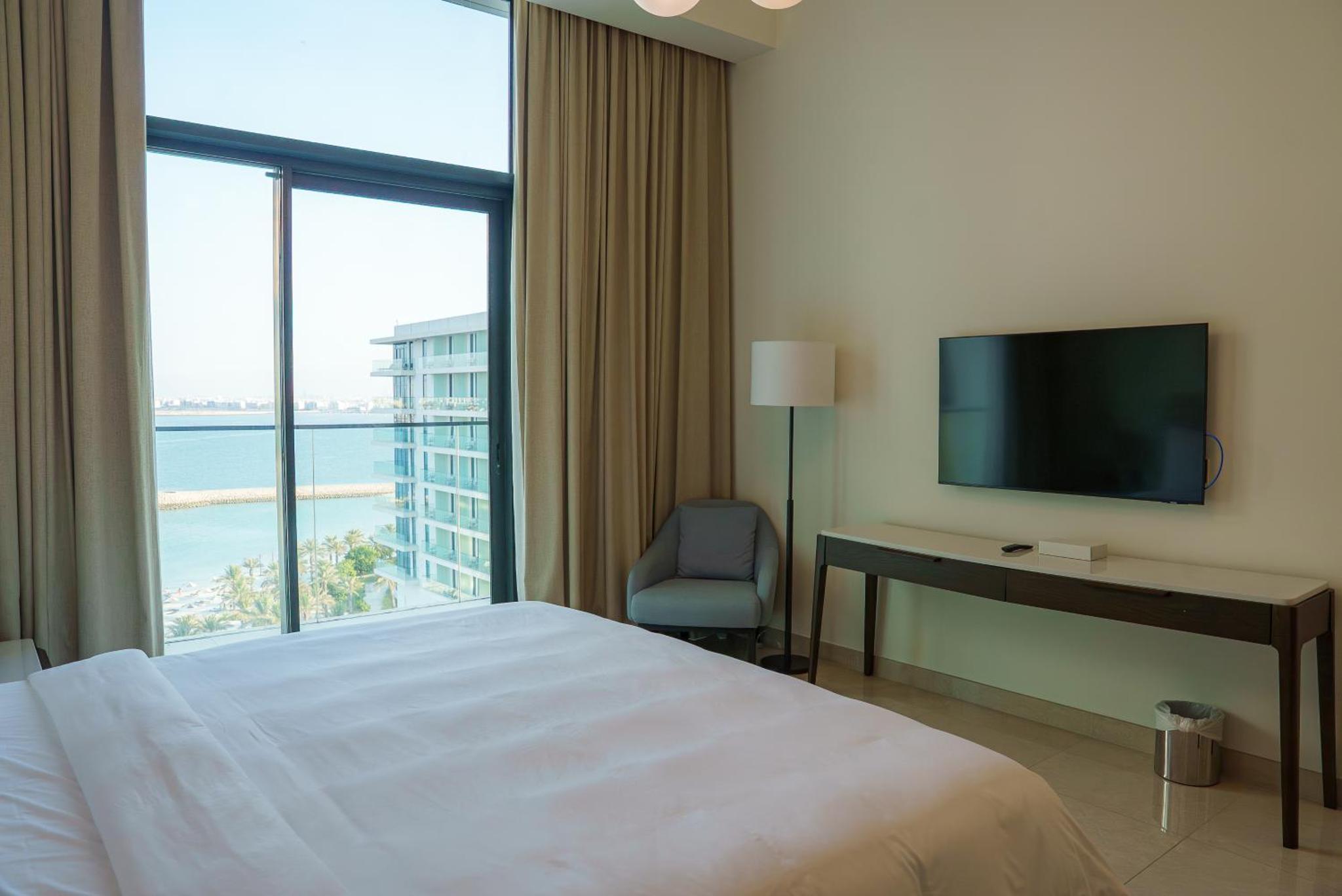 a hotel room with a bed and a desk and a television at Address Beach Resort Residence Bahrain in Rayyā +85 photos