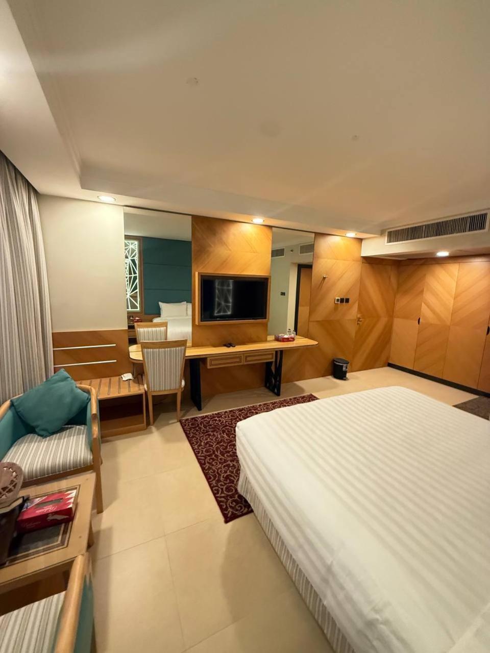 a bedroom with a bed and a table and a desk at Nooh Apartment in Al Ḩadd