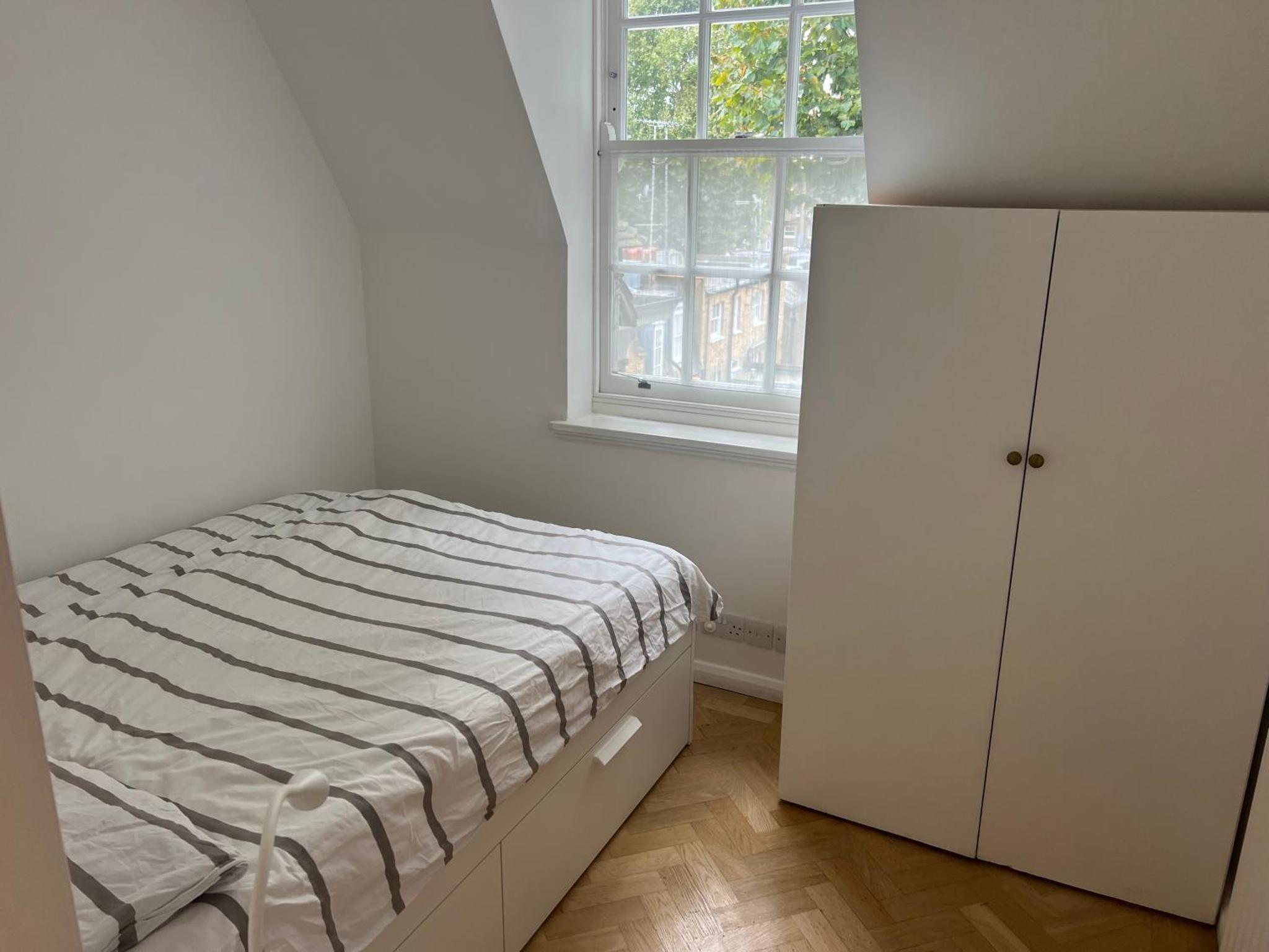 a white bedroom with a bed and a refrigerator at Top view Notting Hill Kensington in London