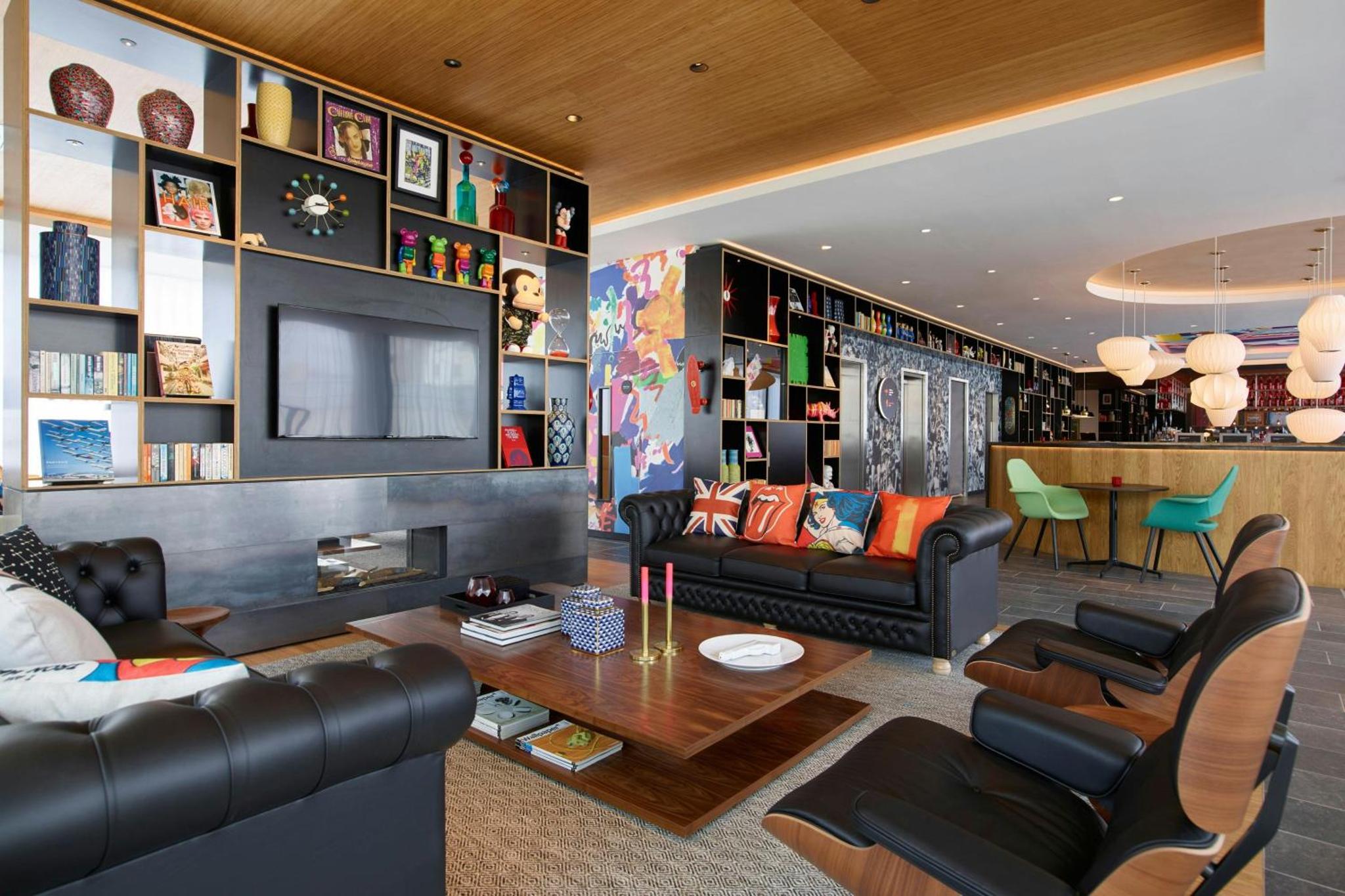 a living room with black leather furniture and a tv at citizenM London Shoreditch in London