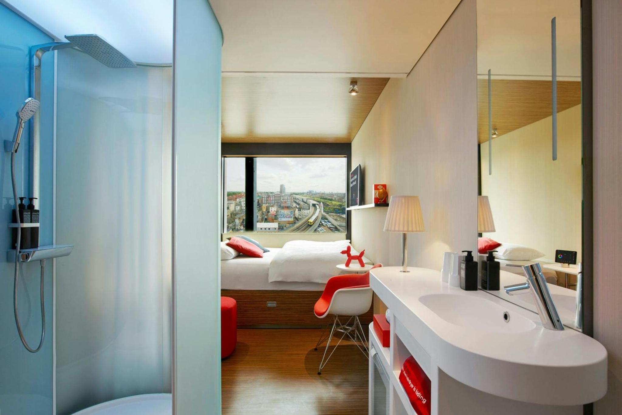 a bathroom with a sink and a bedroom with a bed at citizenM London Shoreditch in London