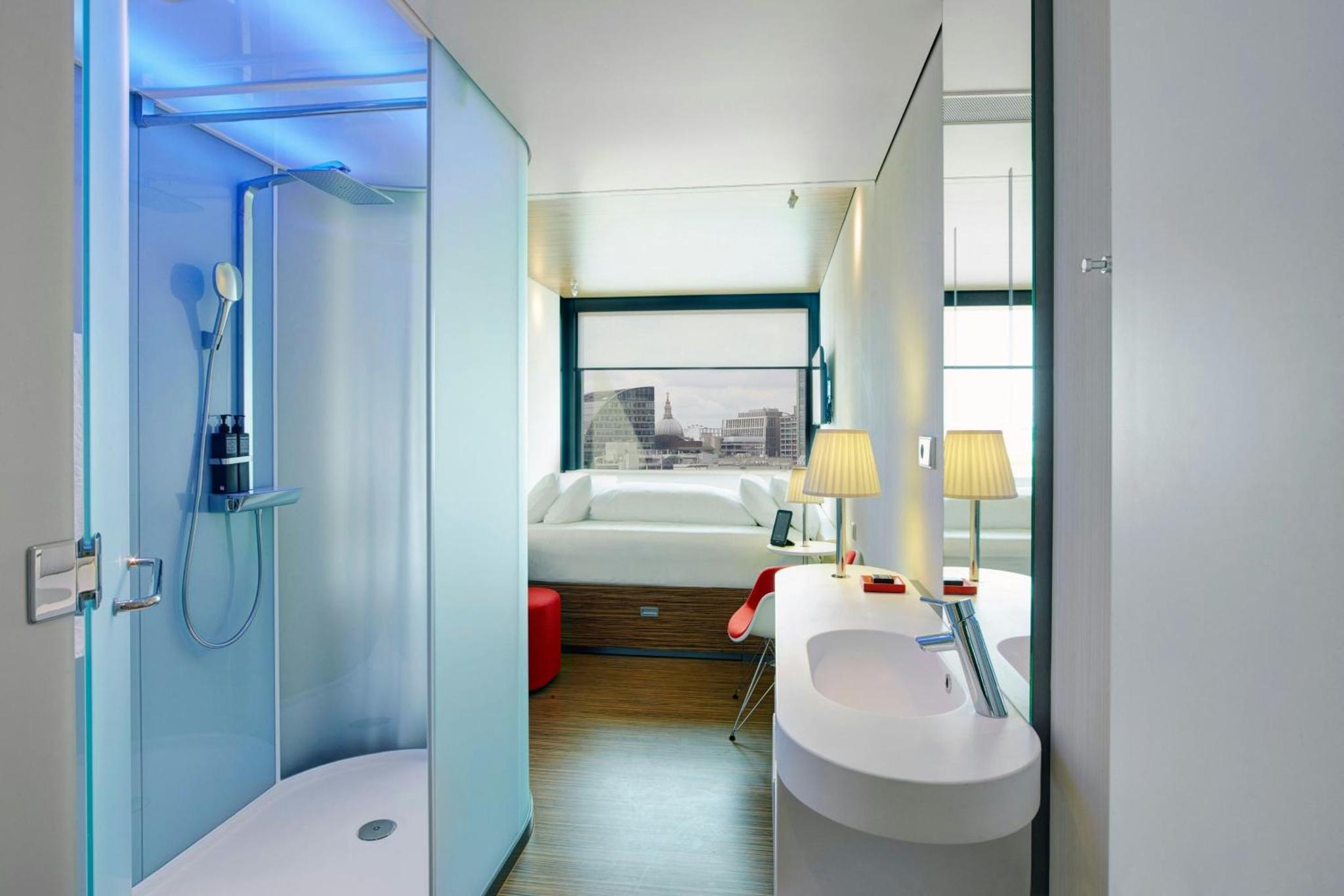 a bathroom with a sink and a shower and a bed at citizenM London Shoreditch in London +21 photos