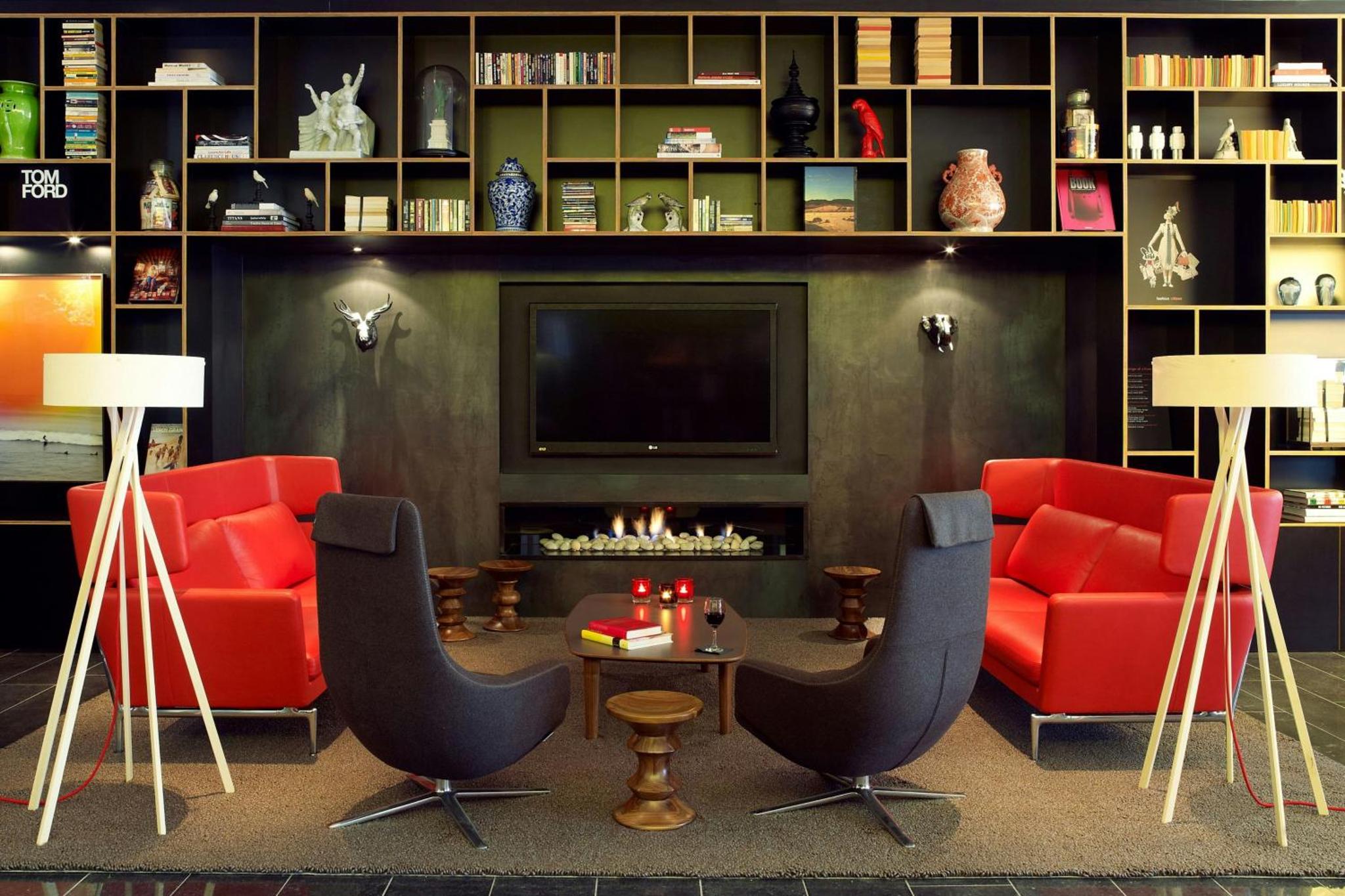 a living room with red furniture and a fireplace at citizenM London Bankside in London +37 photos