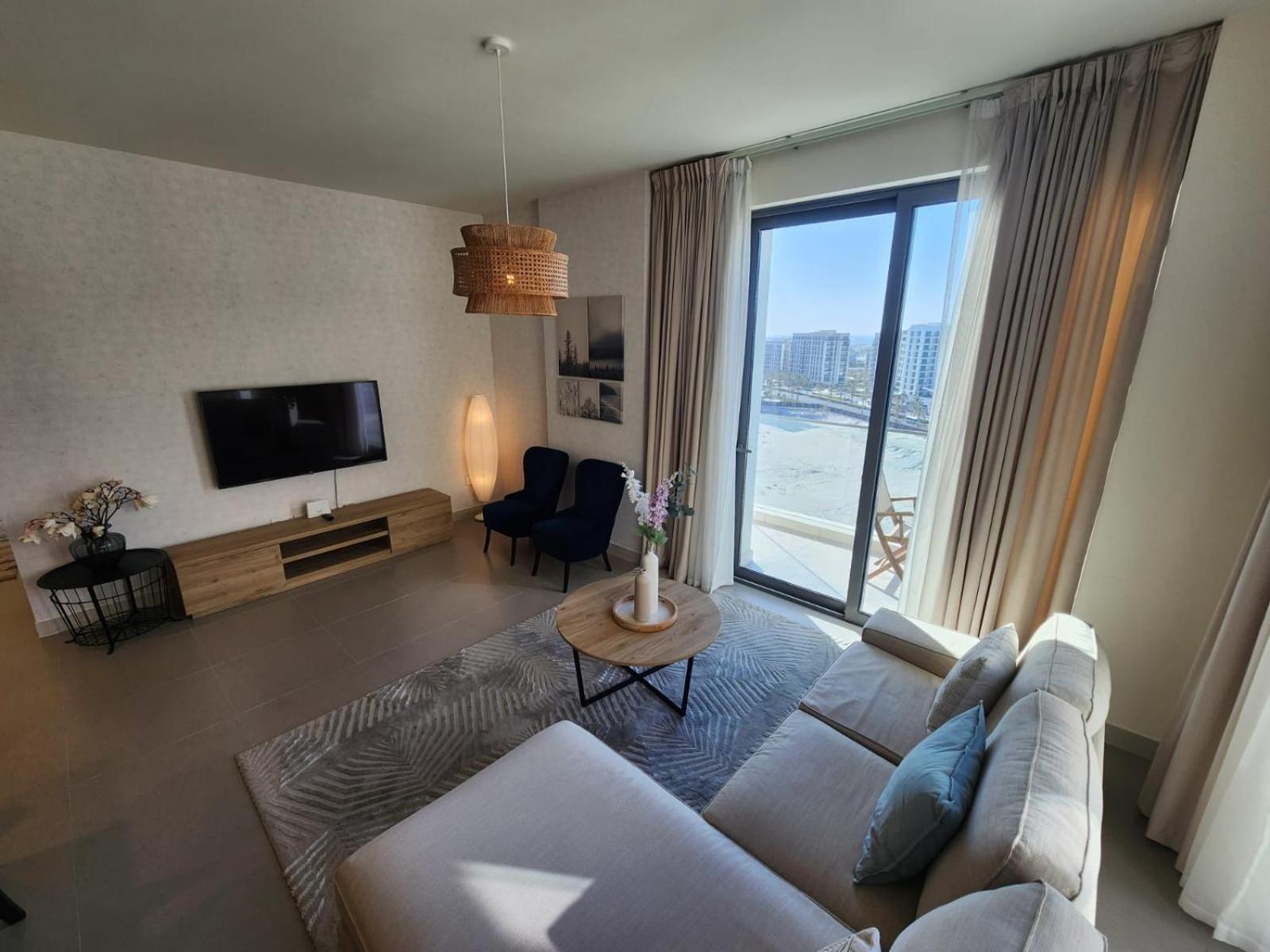 a living room with a white couch and a large window at Elite 2BR Abode Distinctive Living at The Shores in Manama