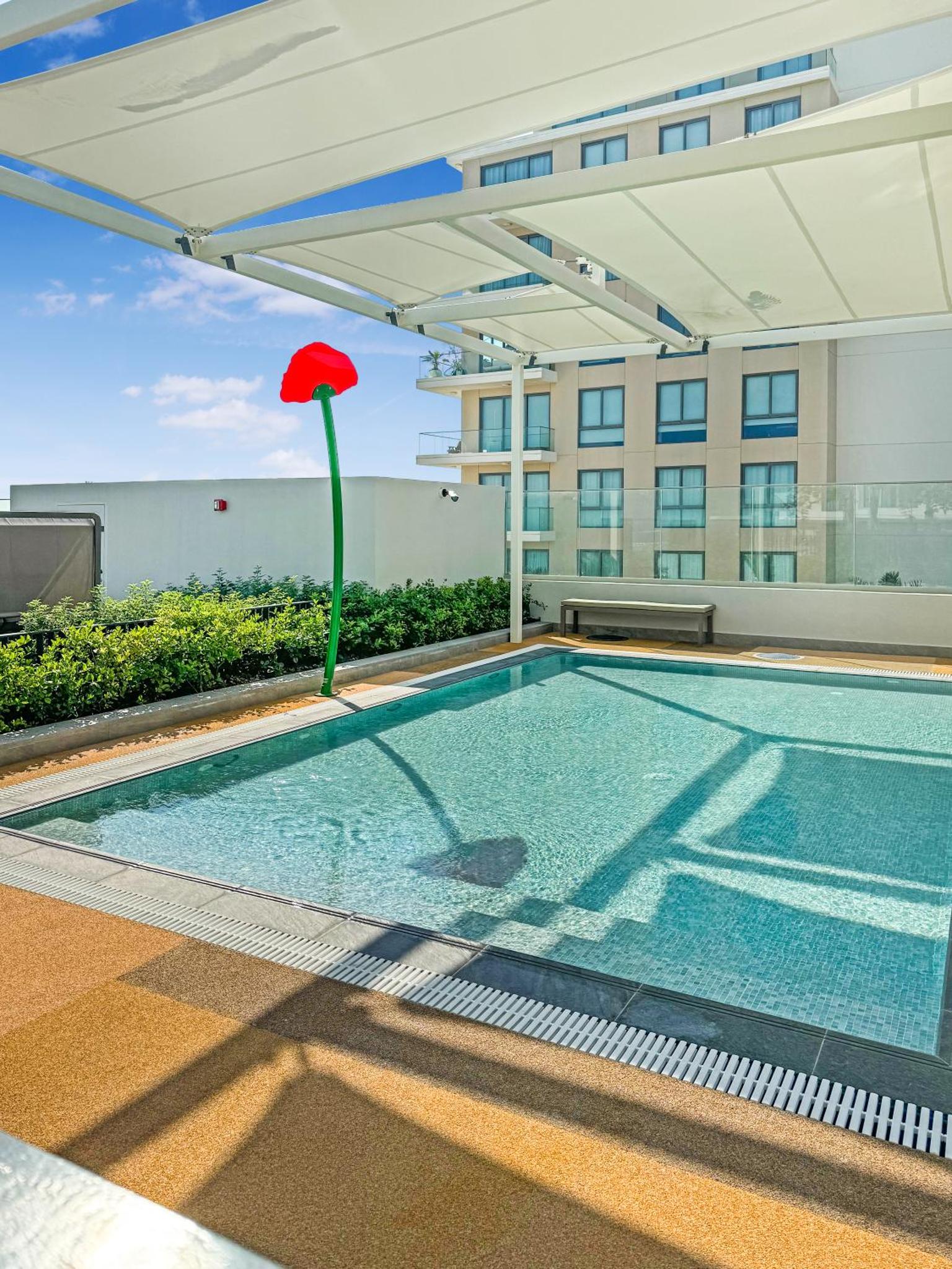 a pool with a red umbrella on top of a building at Marassi Vista 1BR Gem with Beach Access near Mall in Amwaj Island