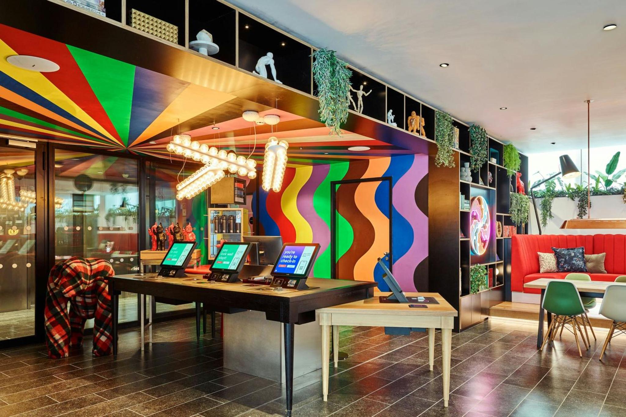 a room with a desk with laptops on it at citizenM London Victoria Station in London