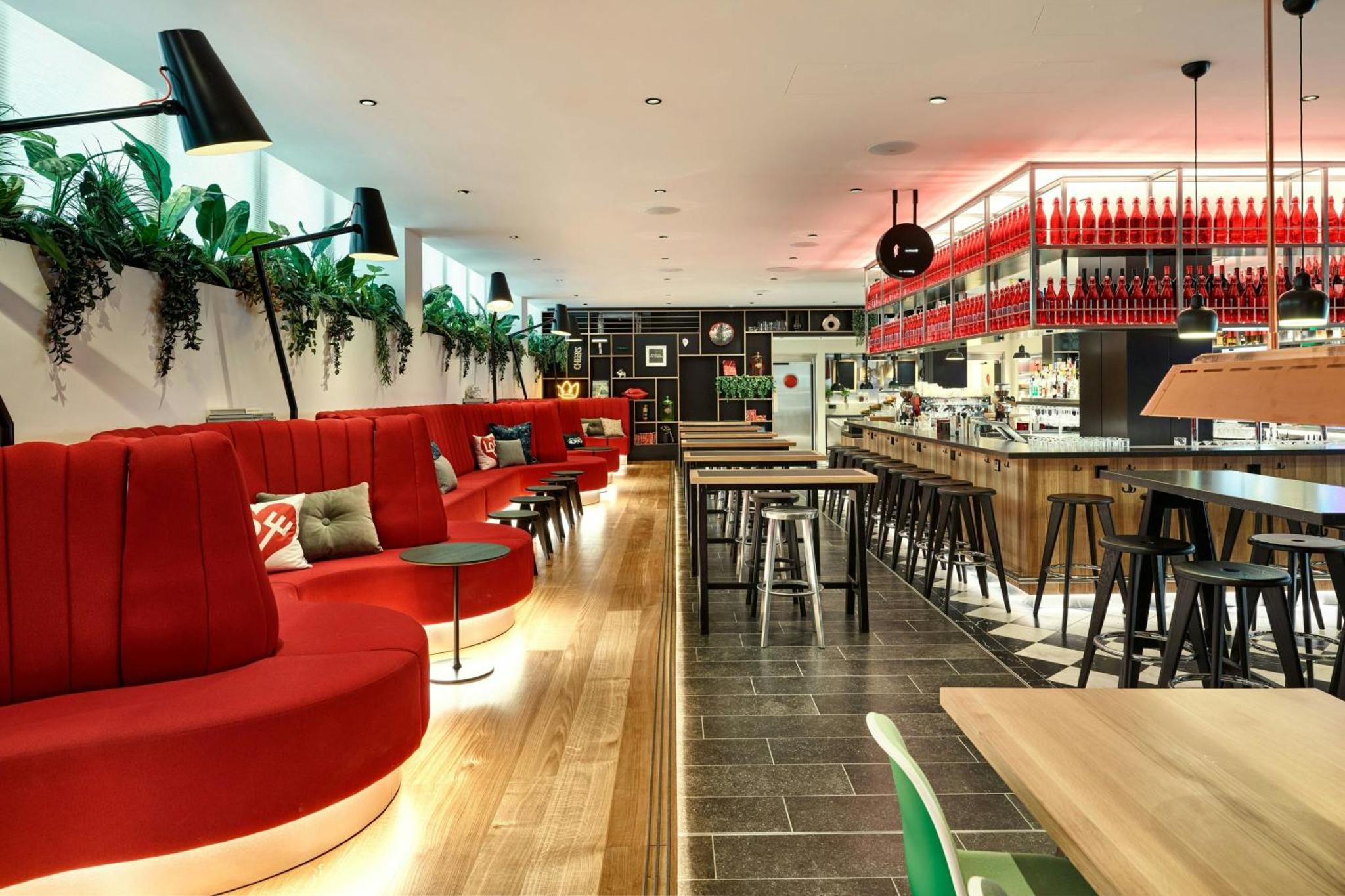 a restaurant with red chairs and a bar at citizenM London Victoria Station in London +22 photos