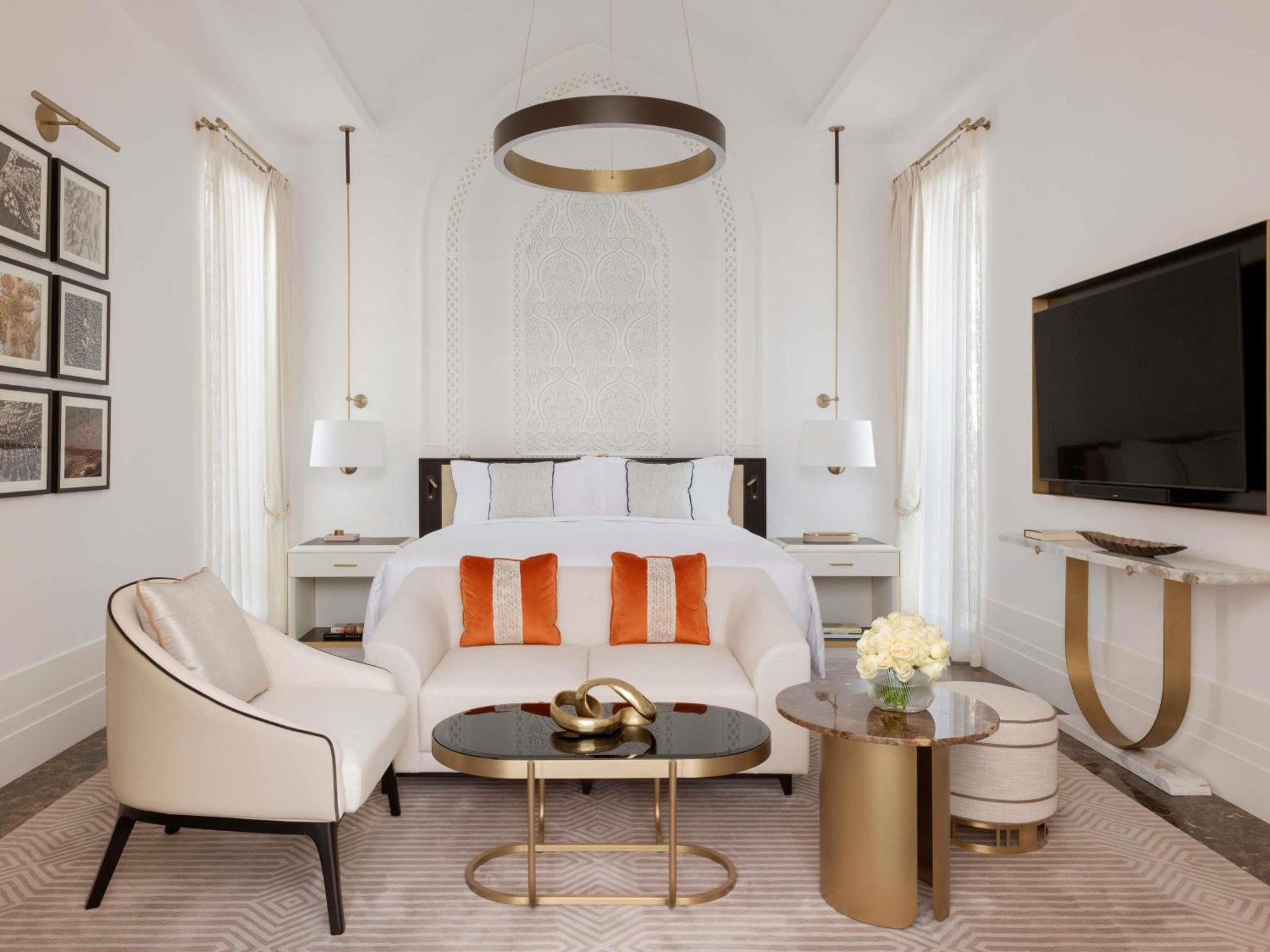a white bedroom with a bed and a couch and a table at Raffles Al Areen Palace Bahrain in Manama