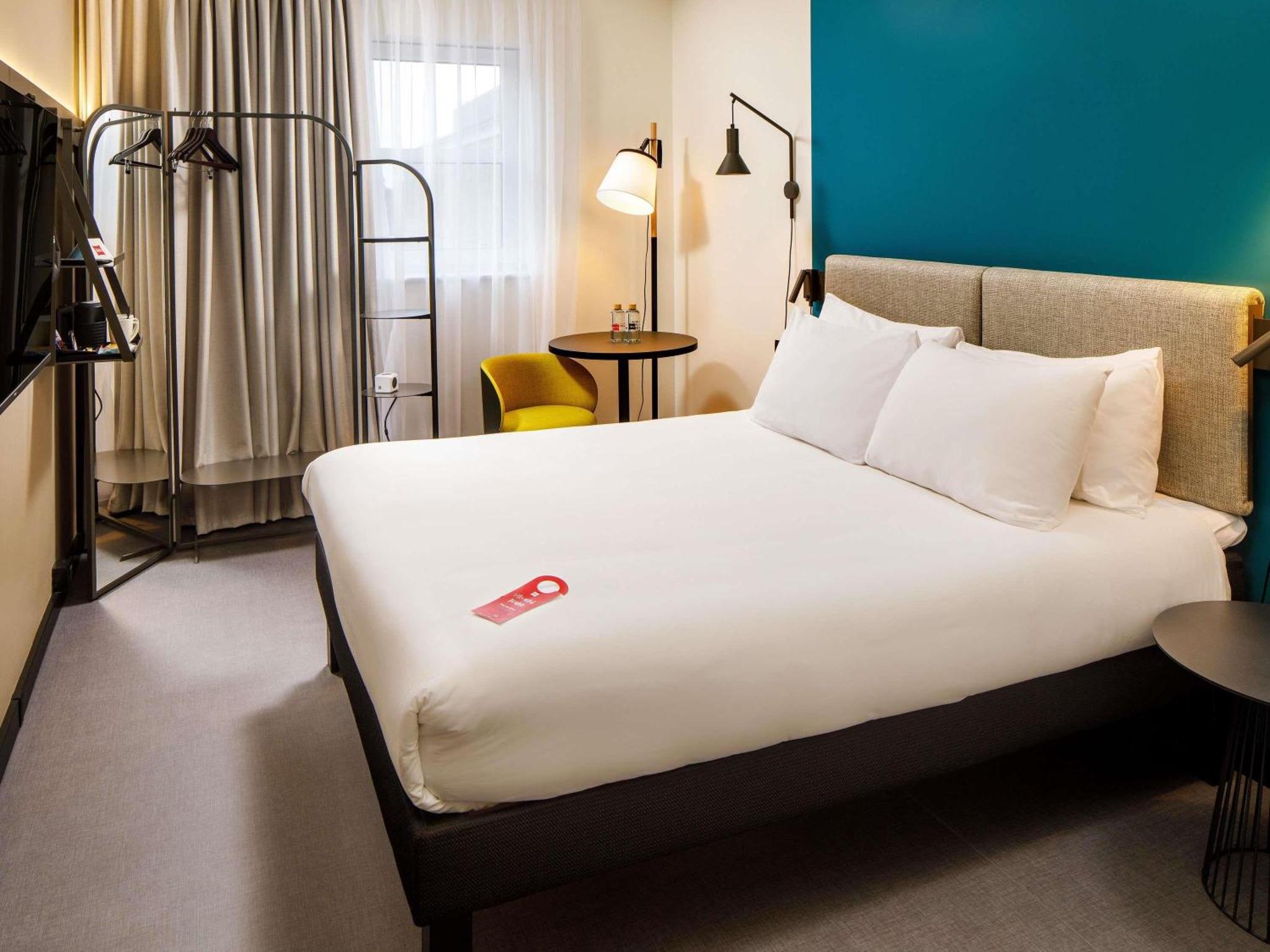 a hotel room with a bed and a chair at ibis London Greenwich in London +80 photos