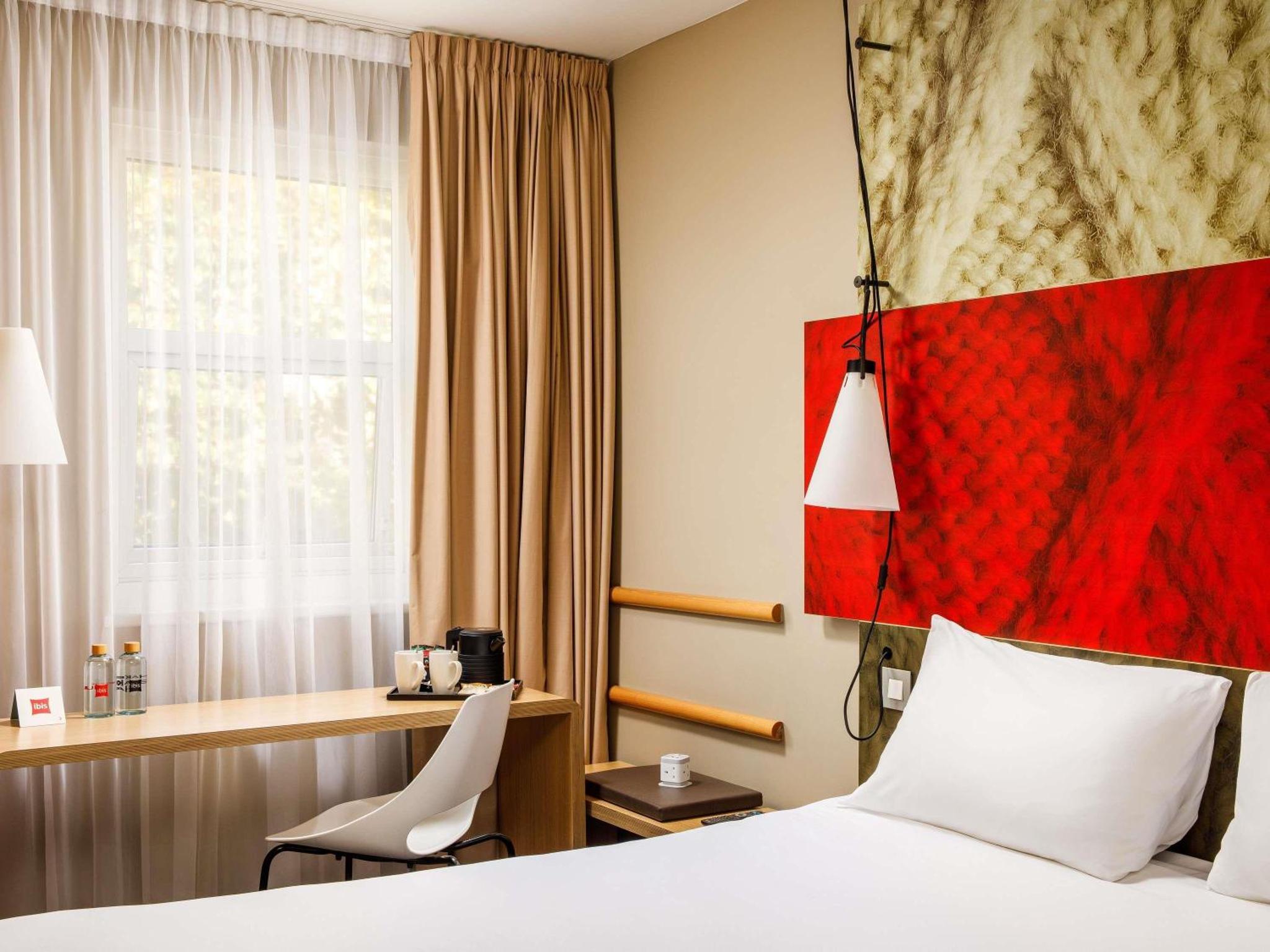 a hotel room with a bed and a desk and a window at ibis London Greenwich in London