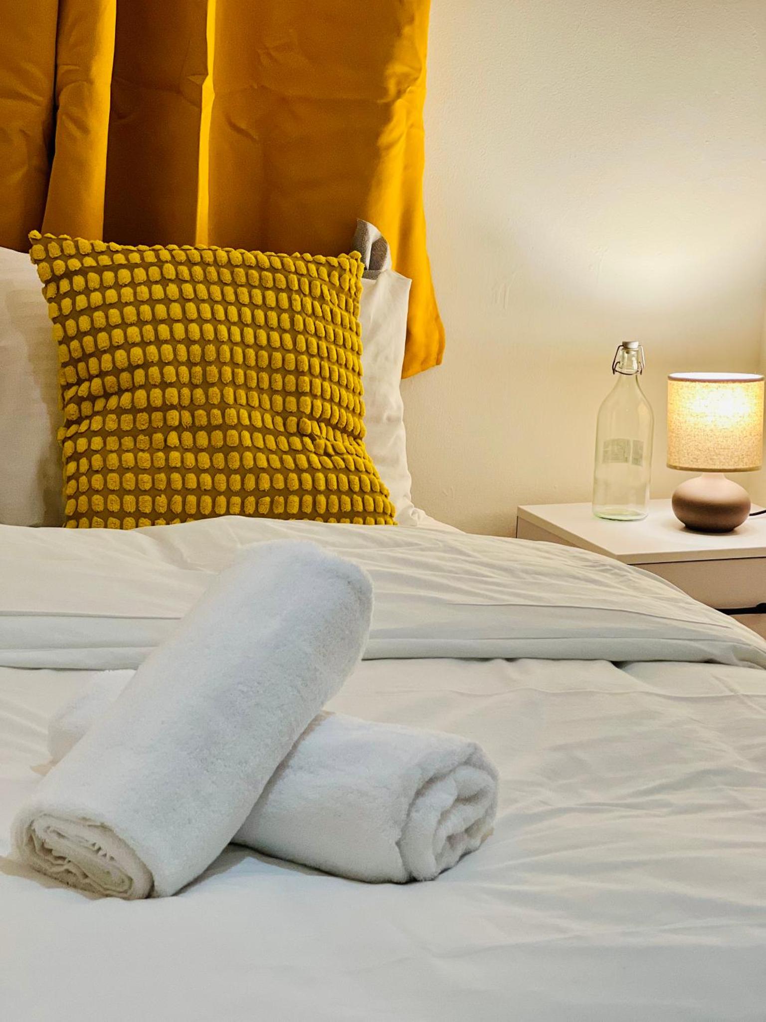 a towel on a bed with a yellow pillow at The Brick Lane Suites London in London +11 photos