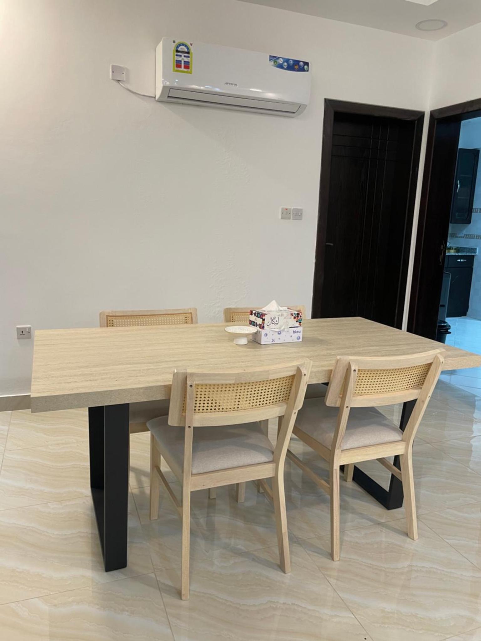 a wooden table with two chairs and a table with at Spacious 2 bedroom apartment in Jazīrat Umm ash Shajar +5 photos