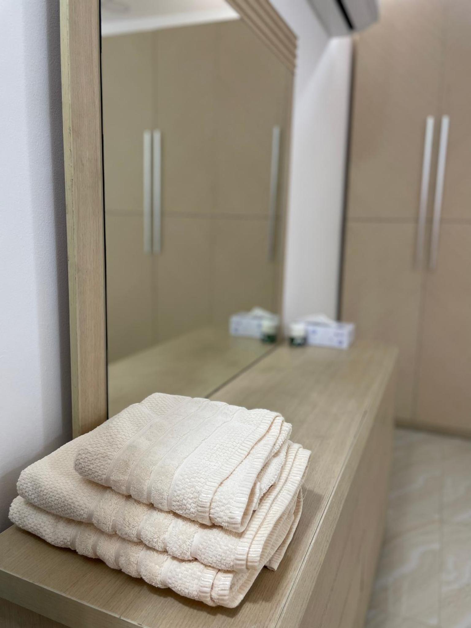 a stack of towels on a counter in front of a mirror at Spacious 2 bedroom apartment in Jazīrat Umm ash Shajar