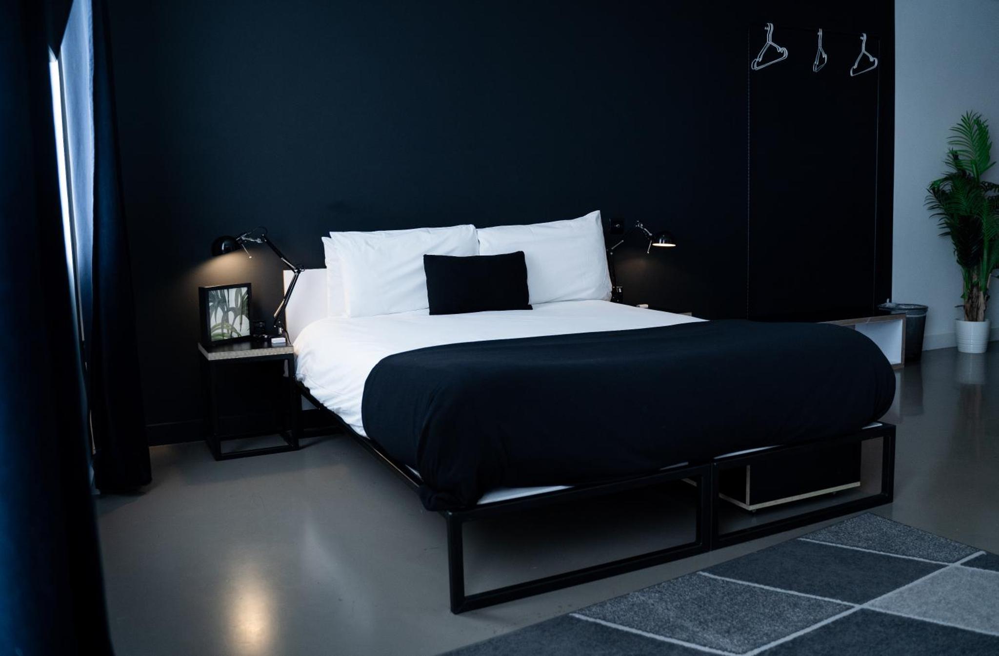 a black bedroom with a large bed with white pillows at Kip Hotel in London