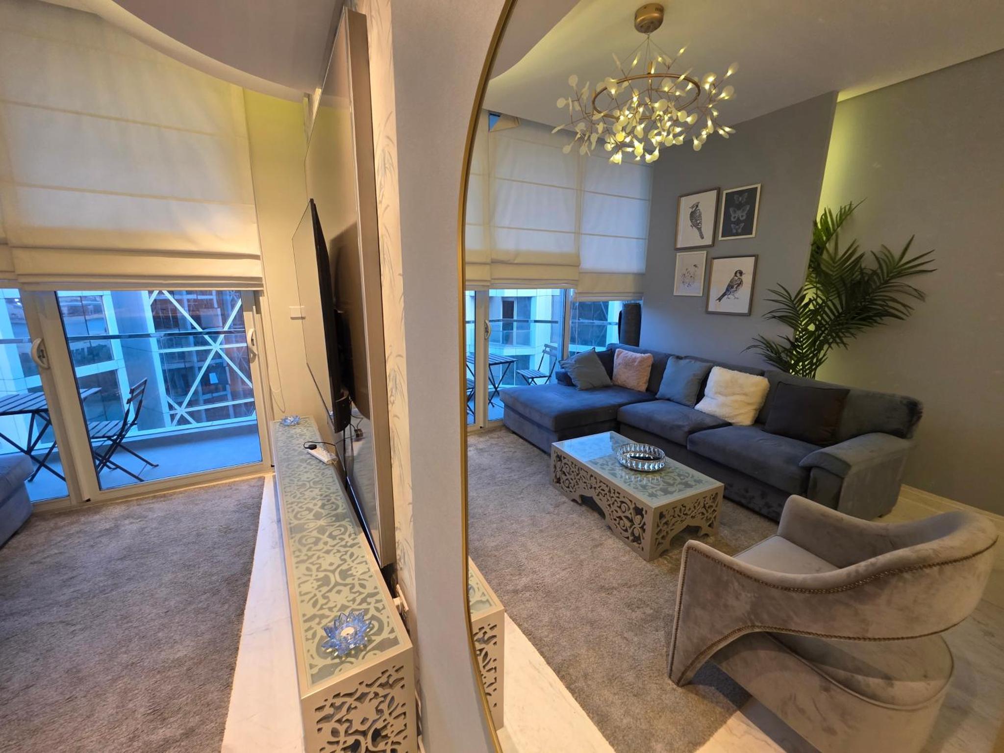 a living room with a blue couch and a mirror at Elite 1BR - Sea View & Four Seasons Scene in Manama